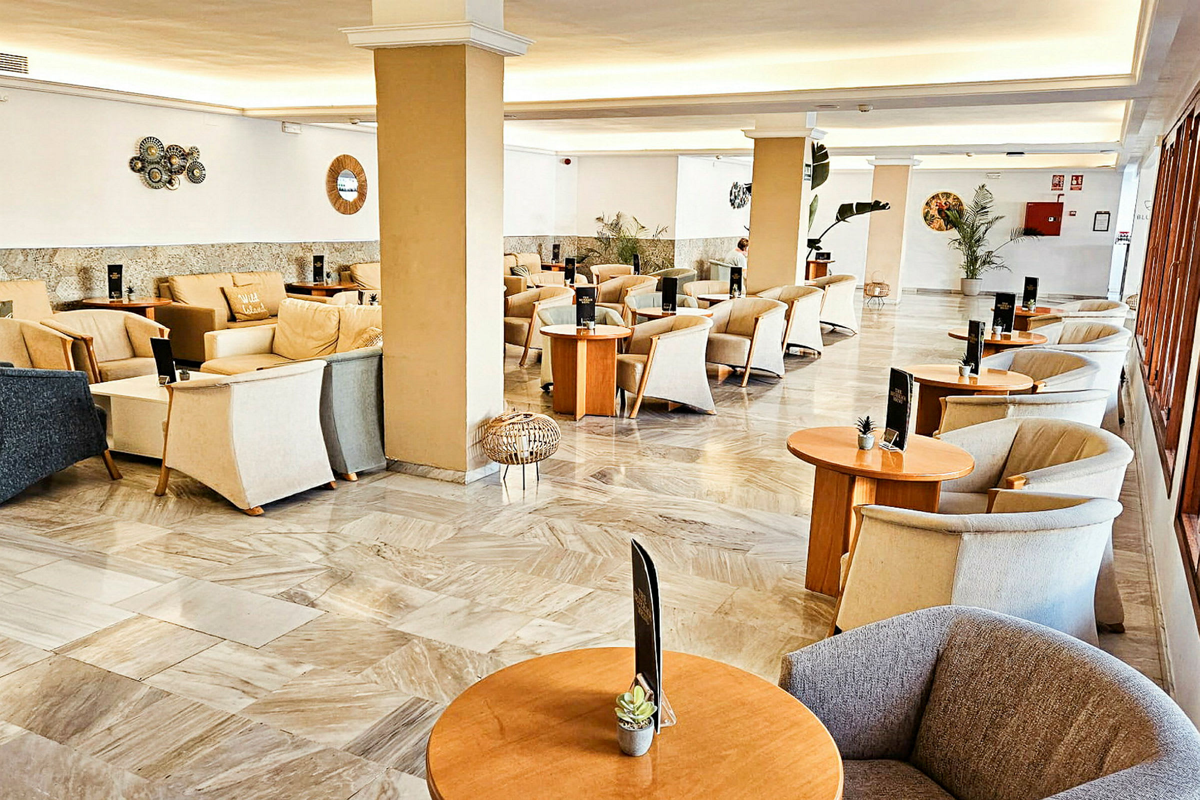 Ljus och rymlig lounge med bekväma stolar och soffor samt små bord. Väggdekorationer och växter skapar en trevlig inomhusmiljö. (AI-genererad text)