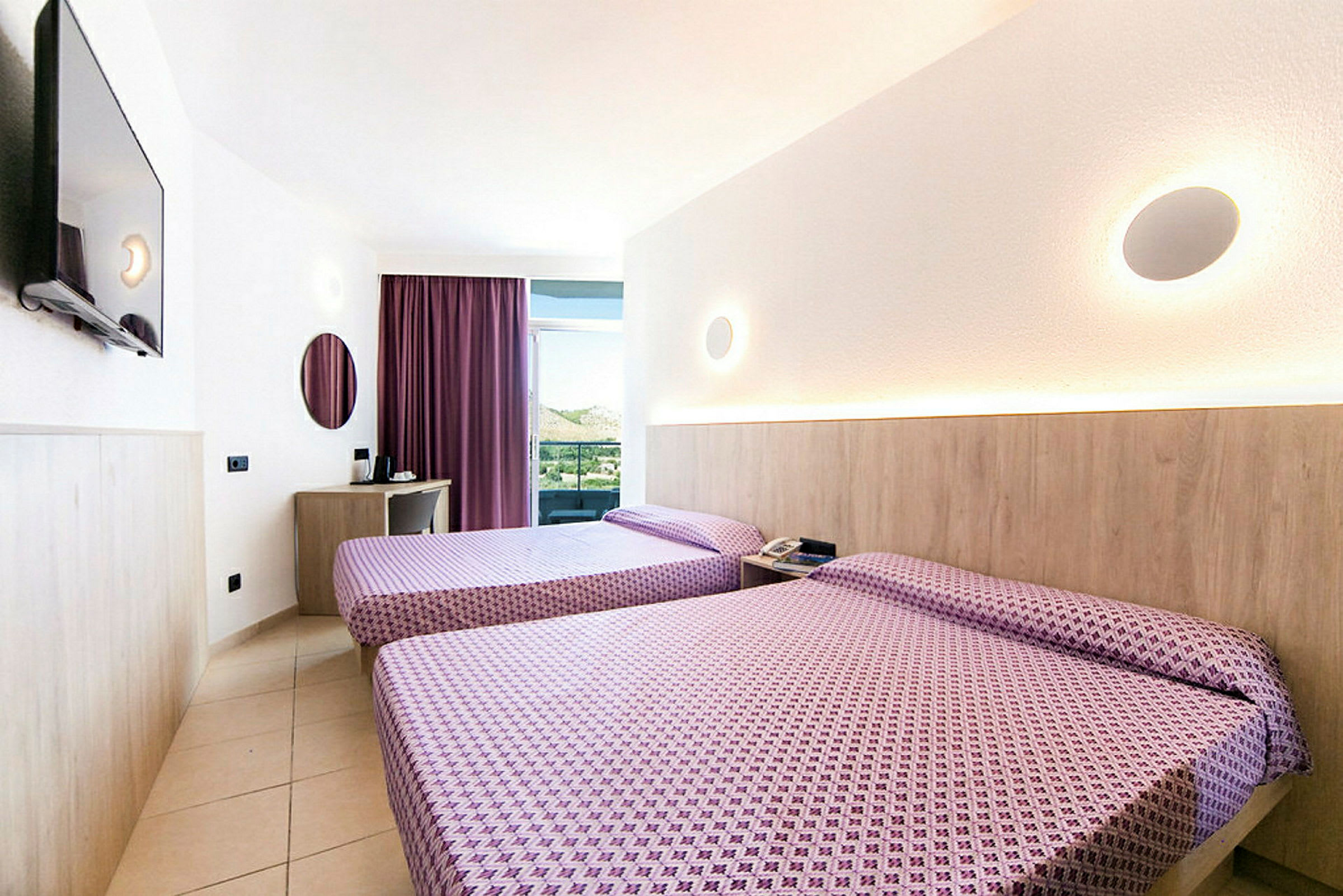 Bild på ett hotellrum med två sängar, ett skrivbord med spegel och TV på väggen. (AI-genererad text)