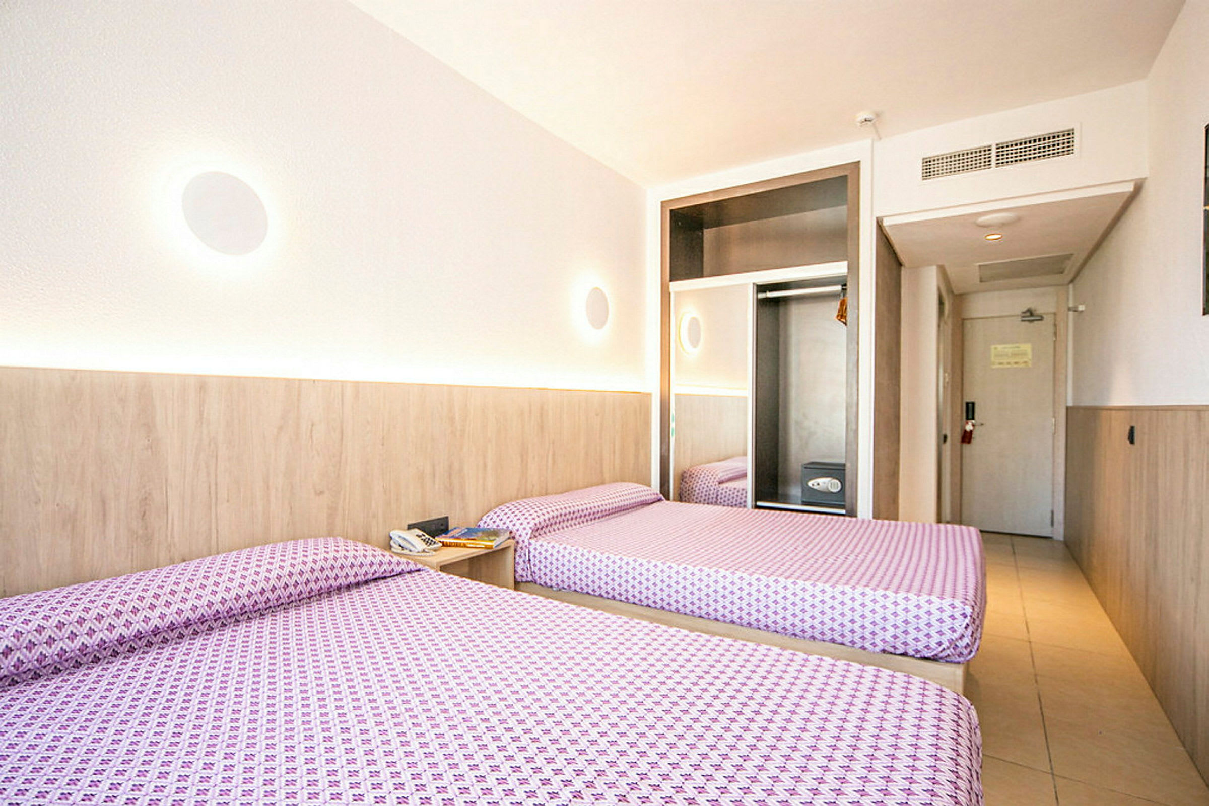 Hotelrum med två enkelsängar, garderob och dörr. (AI-genererad text)