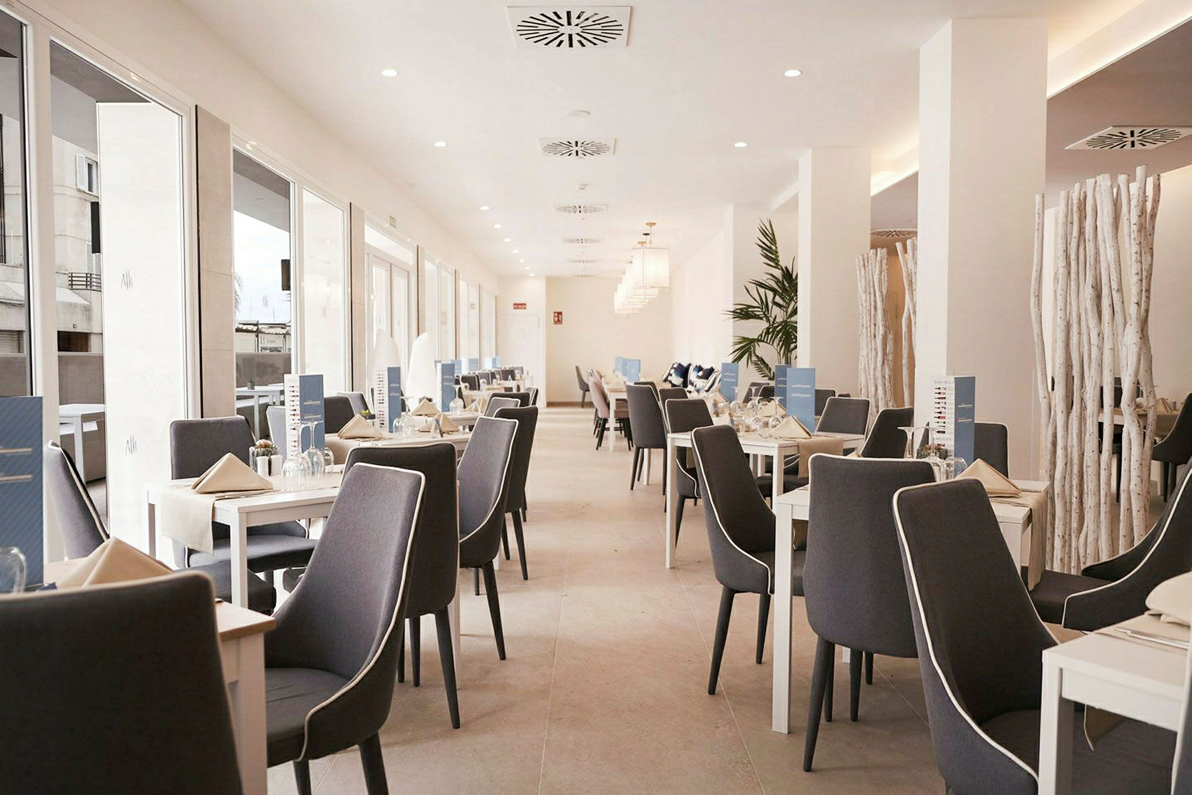 En ljus restaurang med uppställda bord och stolar. (AI-genererad text)