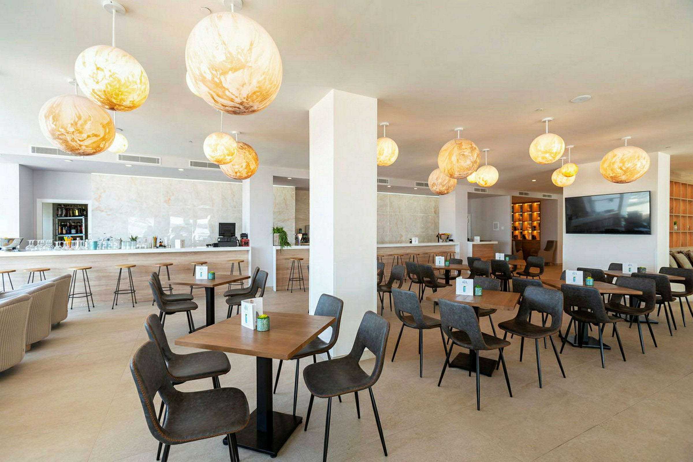 Bild av en restaurang med moderna möbler och hängande dekorativa belysningar. (AI-genererad text)