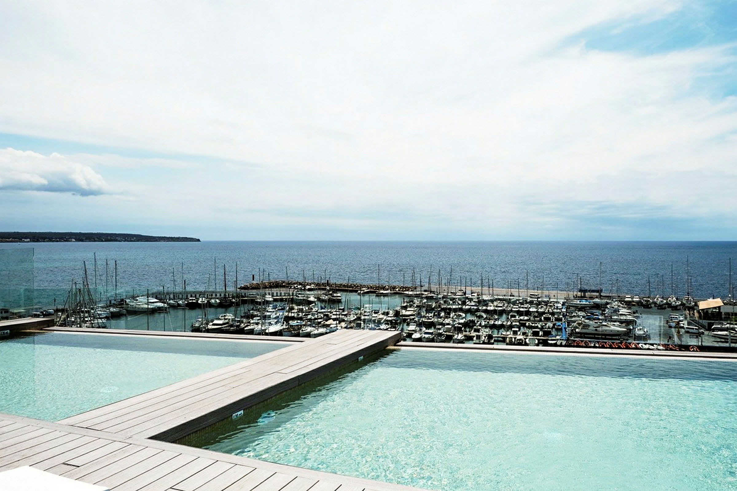 Bild av en infinitypool med utsikt mot en småbåtshamn och havet. (AI-genererad text)