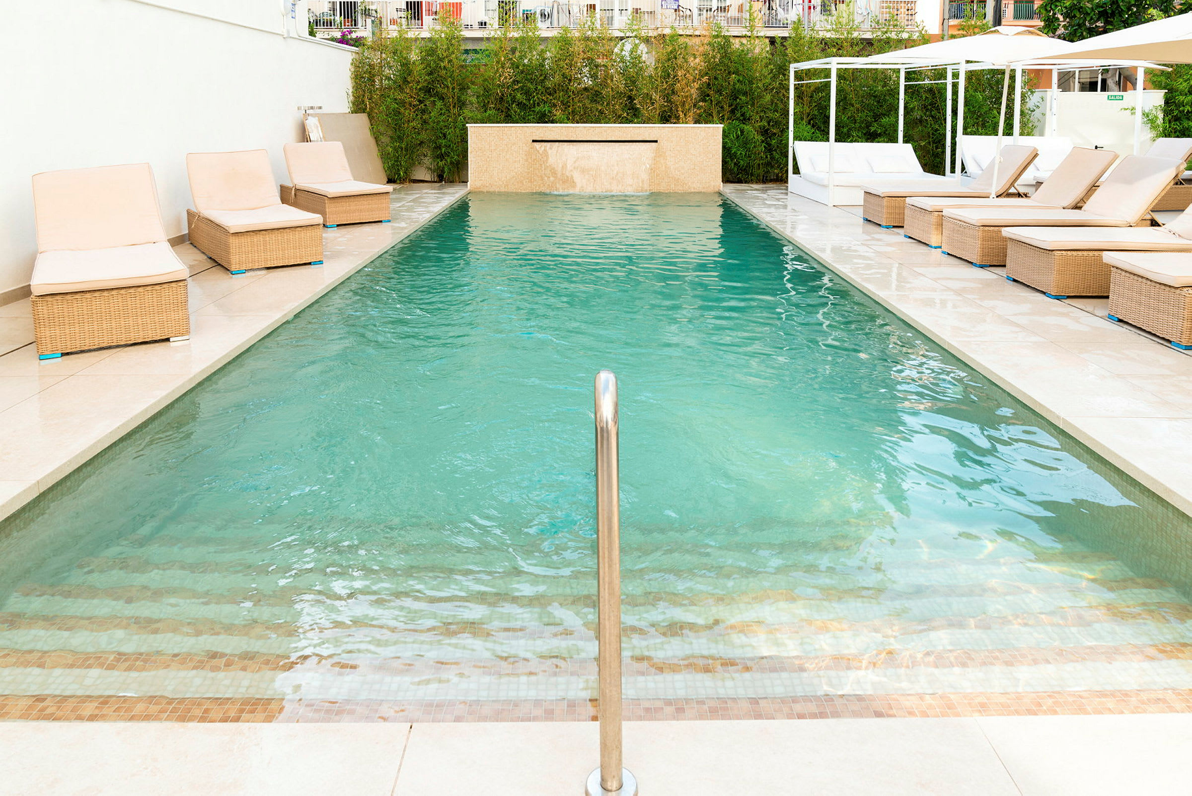 En swimmingpool med solstolar vid kanten. (AI-genererad text)