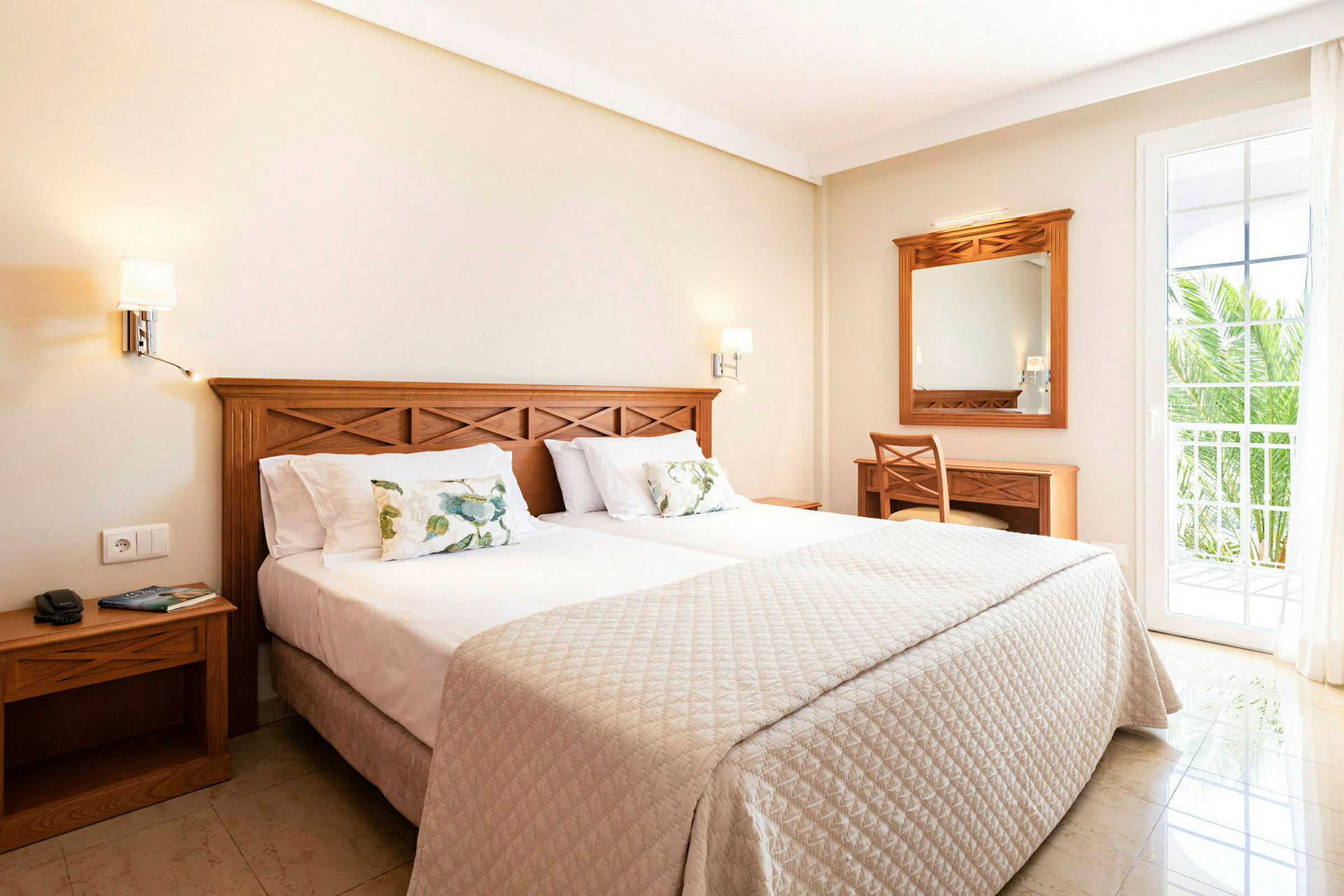 Ett hotellrum med en dubbelsäng, träinredning och en balkongdörr. (AI-genererad text)