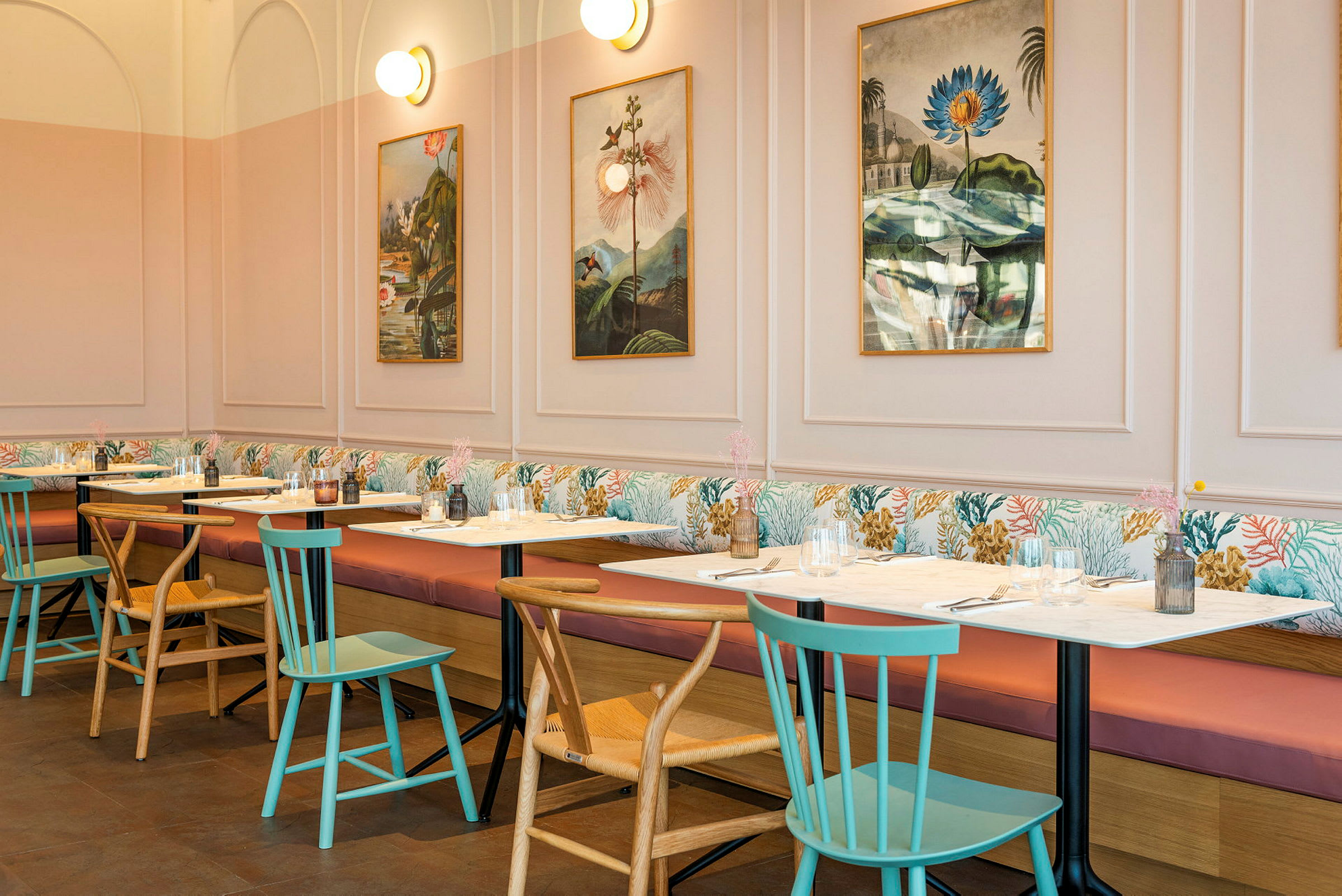 En restaurang med bord och stolar, bilder på väggen och mjuka soffor längs väggen. (AI-genererad text)