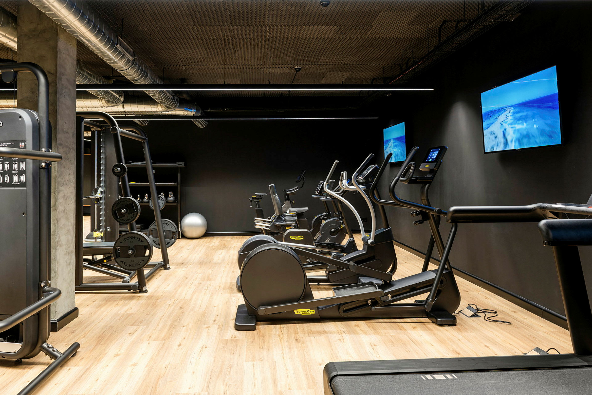 Ett gymrum med träningsutrustning såsom löpband, motionscyklar och en kabelmaskin. (AI-genererad text)