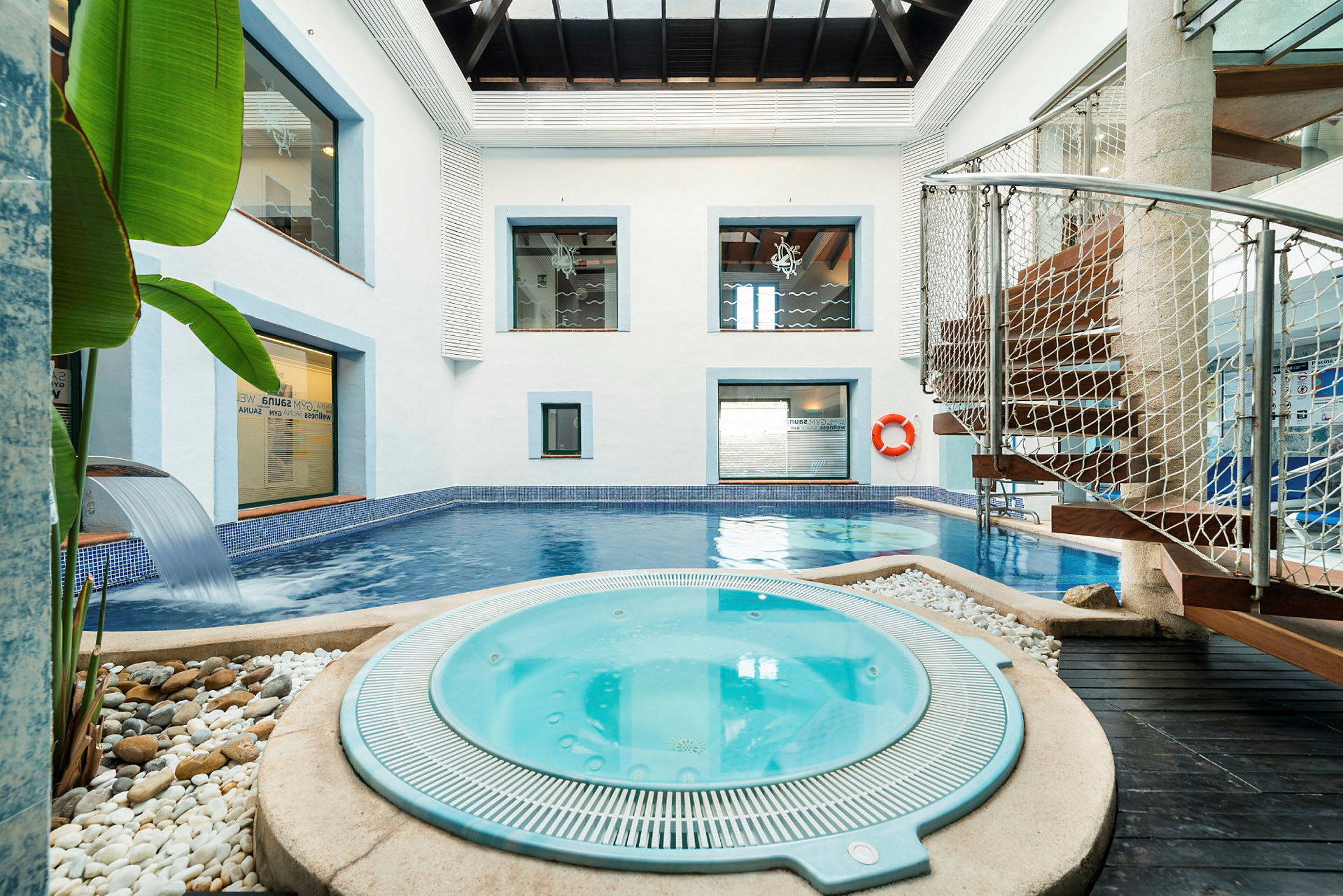 Inomhusspa med en pool och jacuzzi omgiven av moderna detaljer. (AI-genererad text)