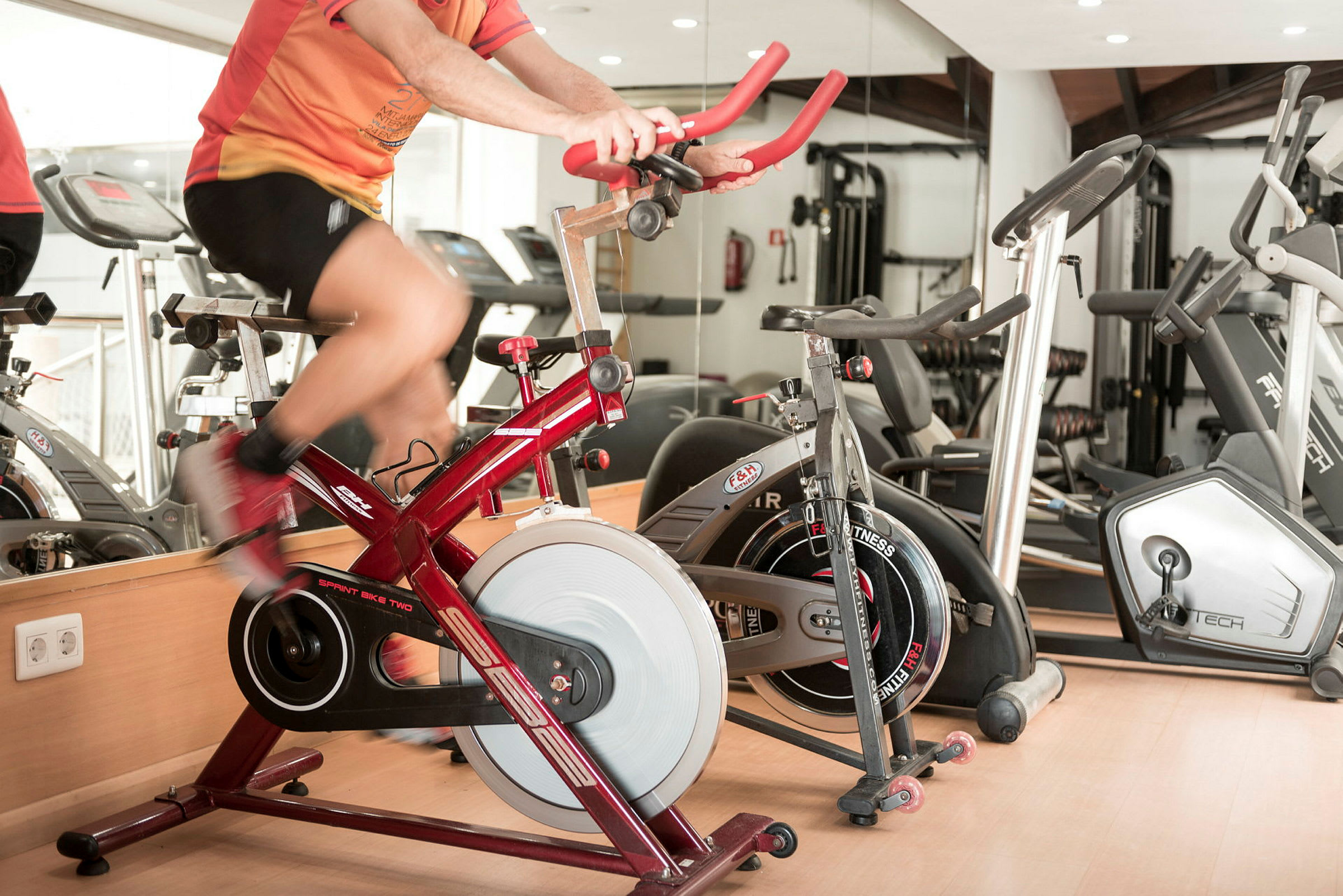 Person tränar på en röd motionscykel i ett gym. (AI-genererad text)