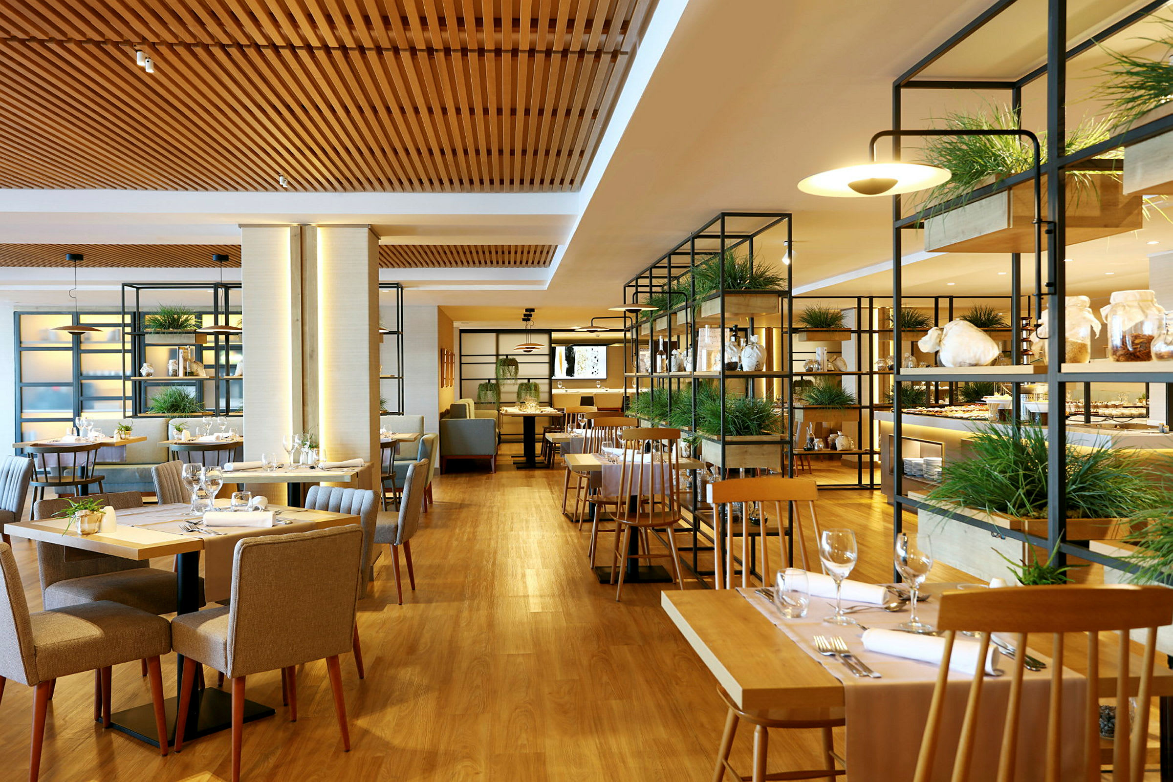 Bild av en modern restaurang med träbord och stolar, växter och glashyllor. (AI-genererad text)
