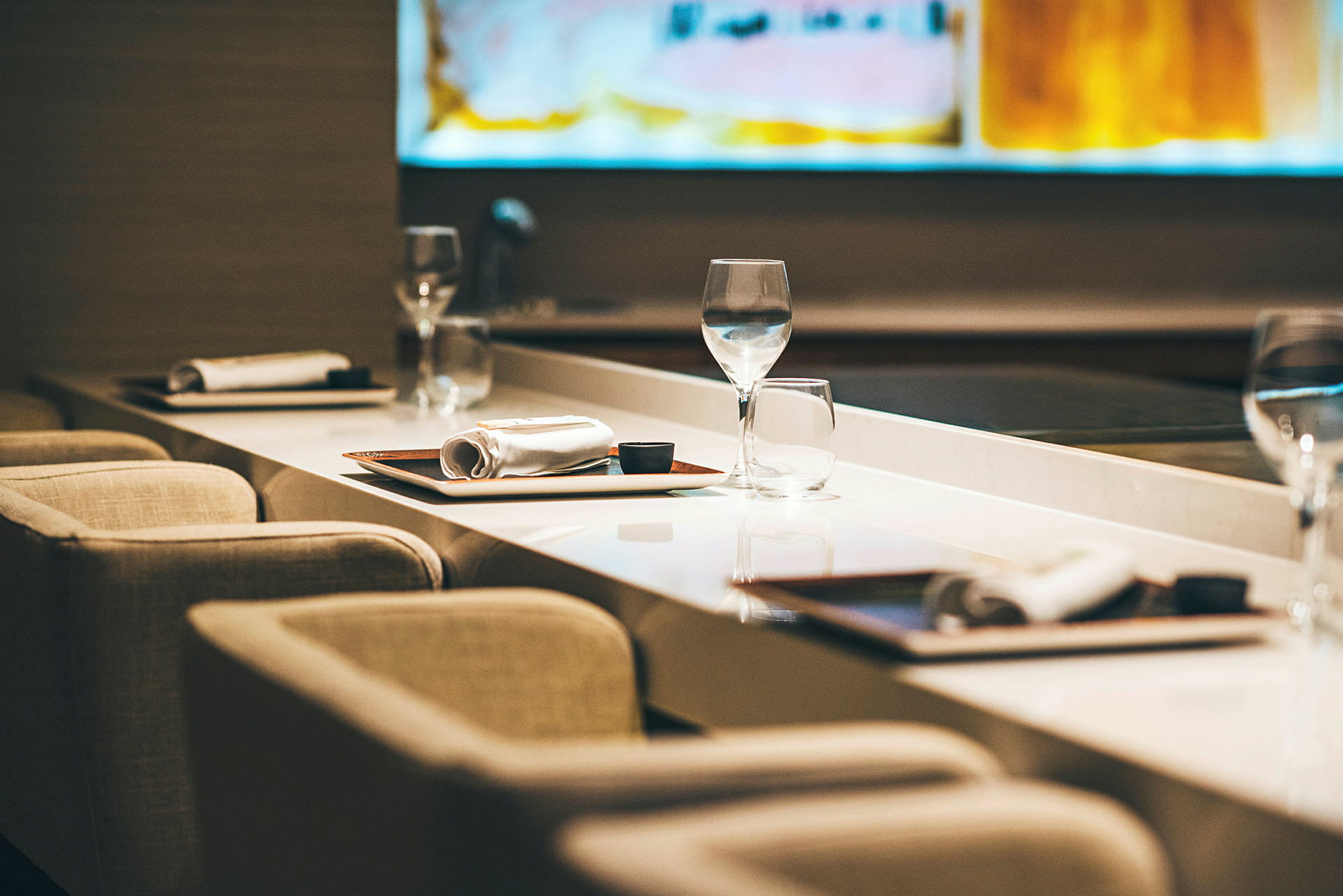 En rad av bord med dukning, inklusive glas, tallrikar och servetter, i en avslappnad restaurangmiljö. (AI-genererad text)