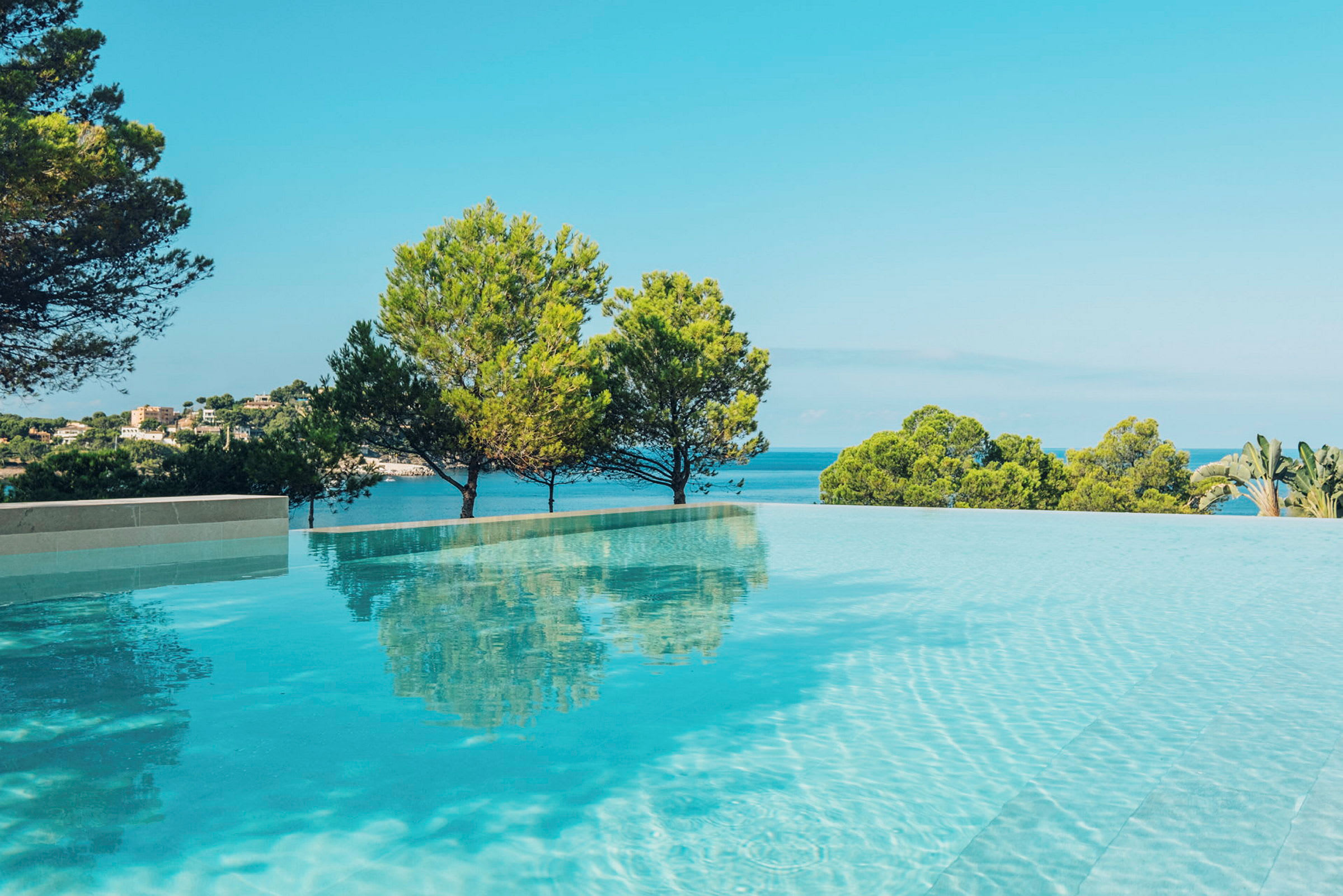 En infinitypool med utsikt över havet och träd i bakgrunden. (AI-genererad text)
