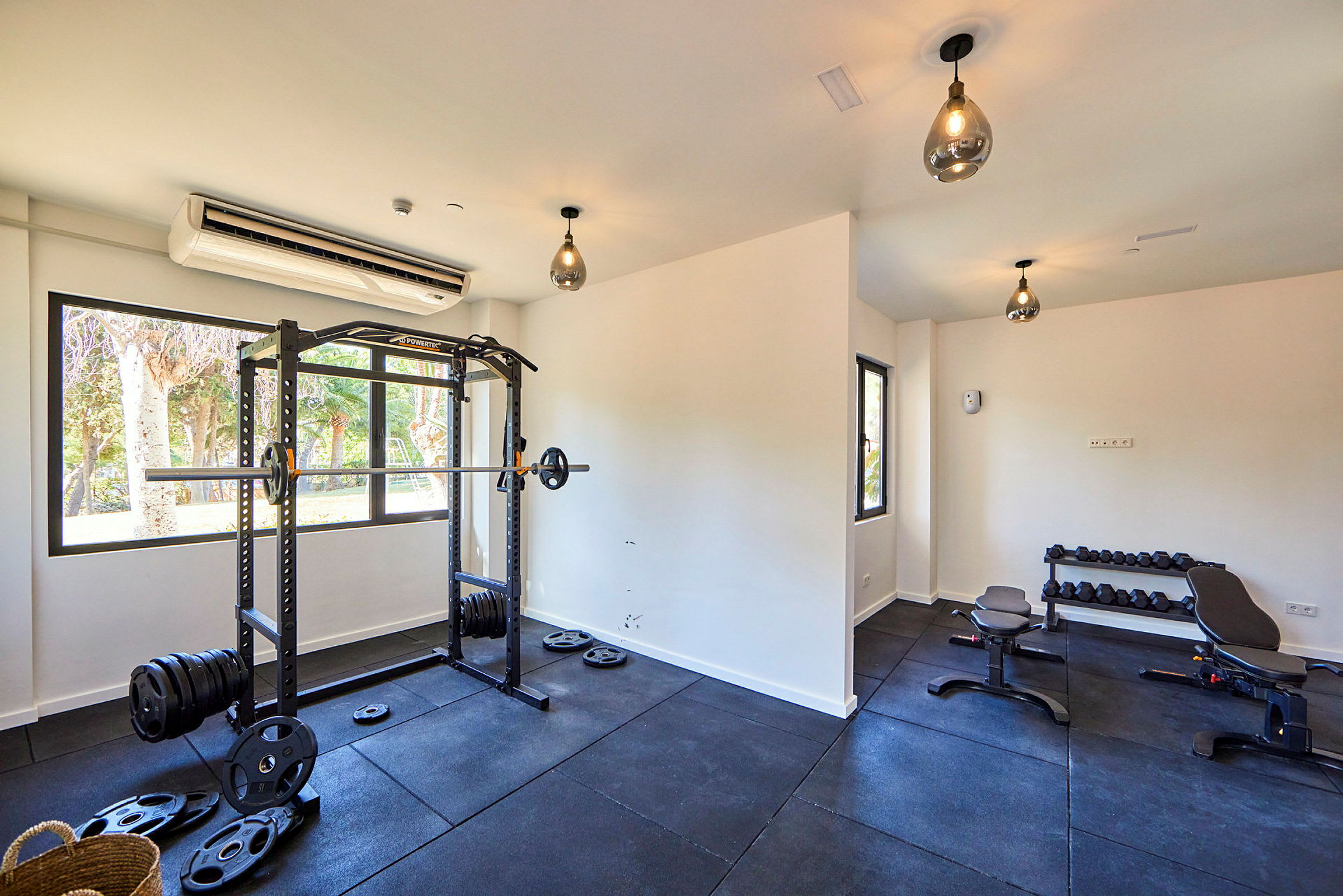 Ett gym med en skivstångsställning, bänkar och hantlar. (AI-genererad text)