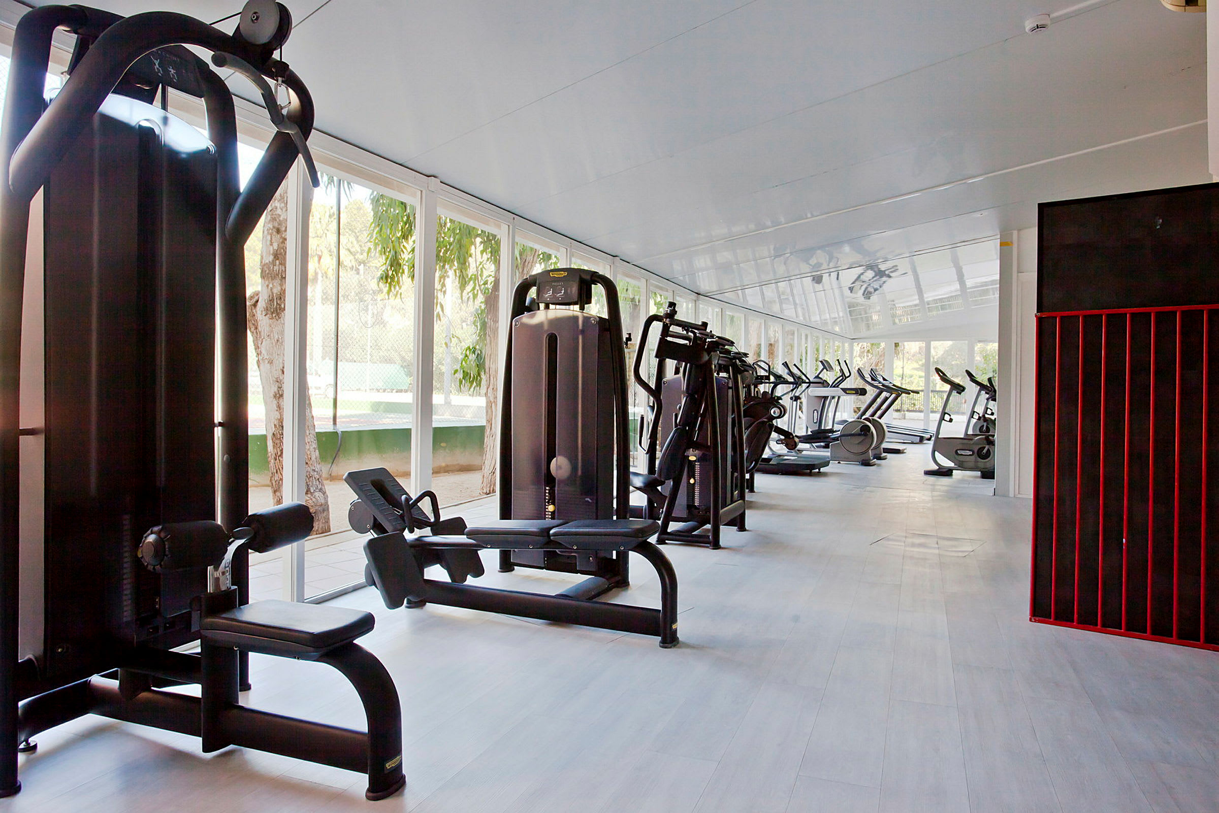 Ett gym med olika träningsmaskiner, med stora fönster som släpper in naturligt ljus. (AI-genererad text)