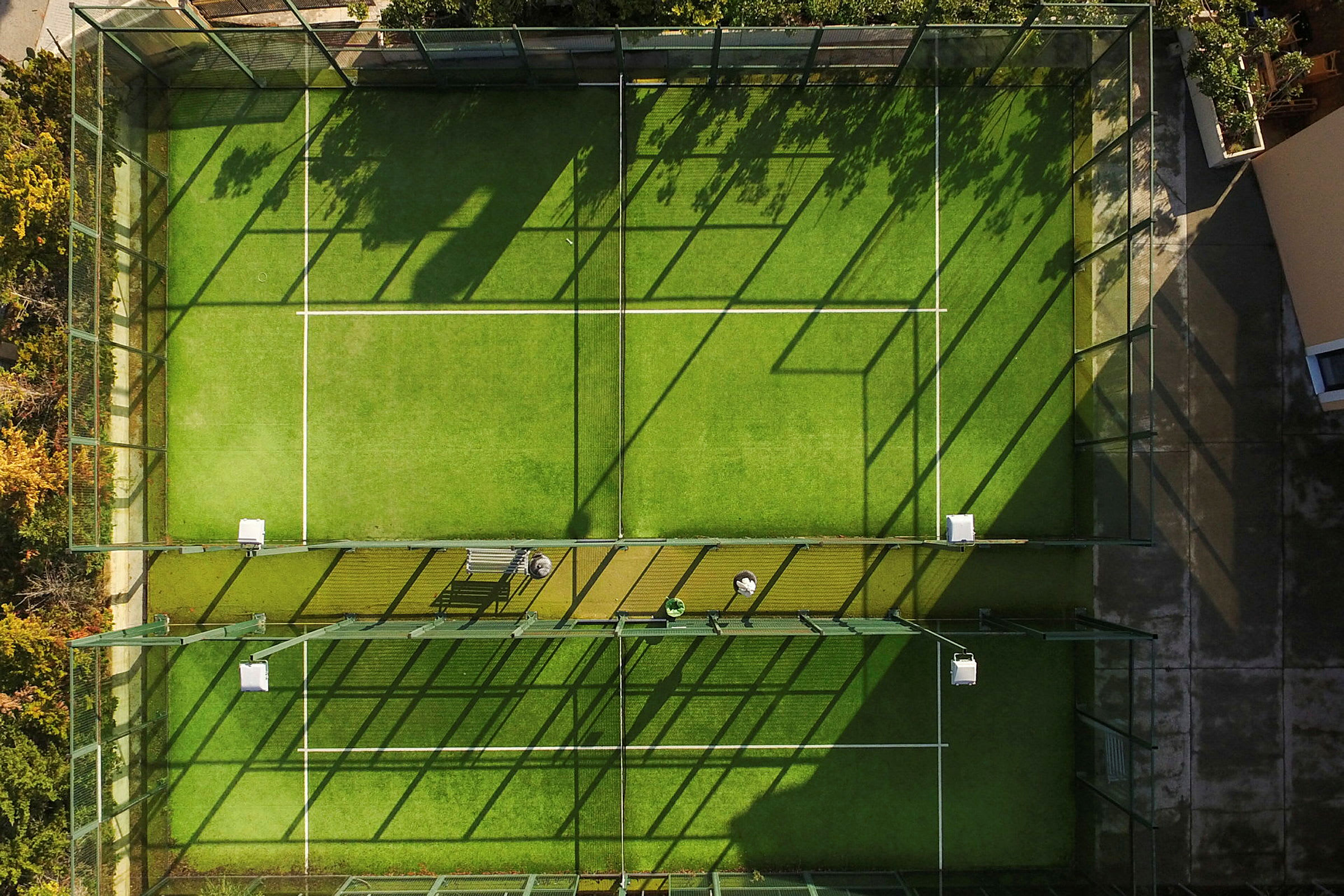 Flygfoto av en inhägnad padelbana med grön konstgräsbeläggning. (AI-genererad text)