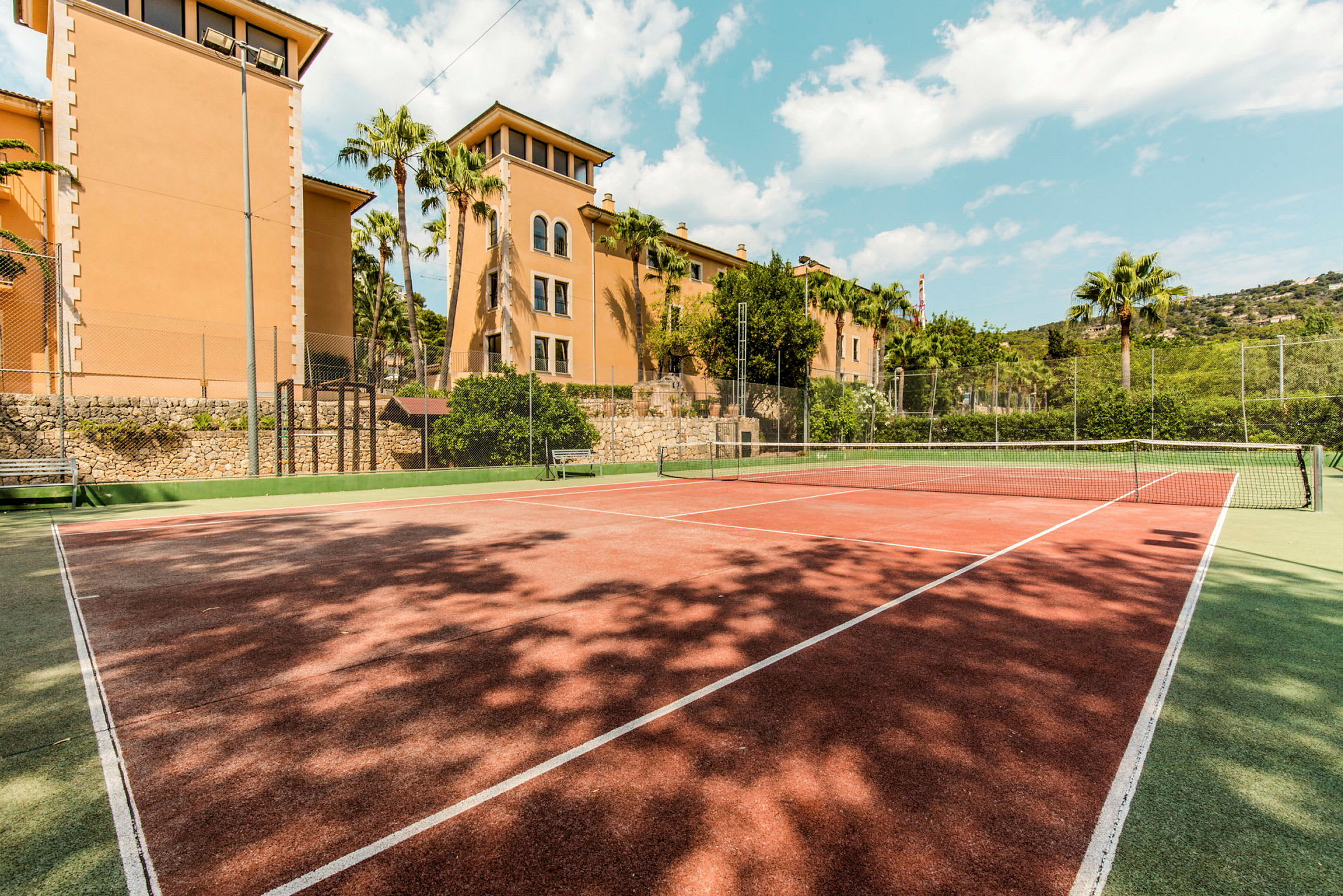 Tennisbana framför byggnader och palmer. (AI-genererad text)