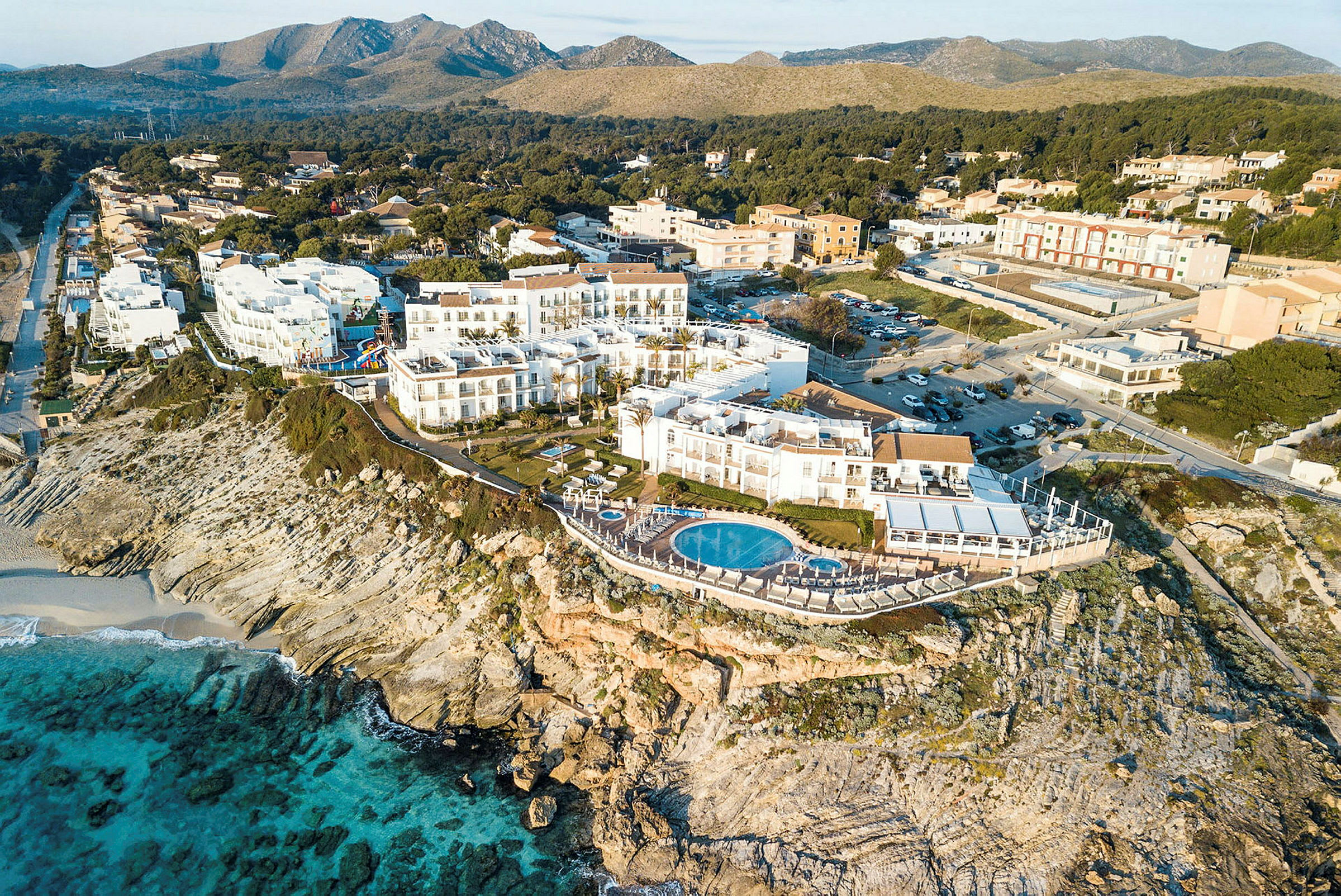 Flygfoto över ett hotell vid en klippa med pool och utsikt över havet. (AI-genererad text)