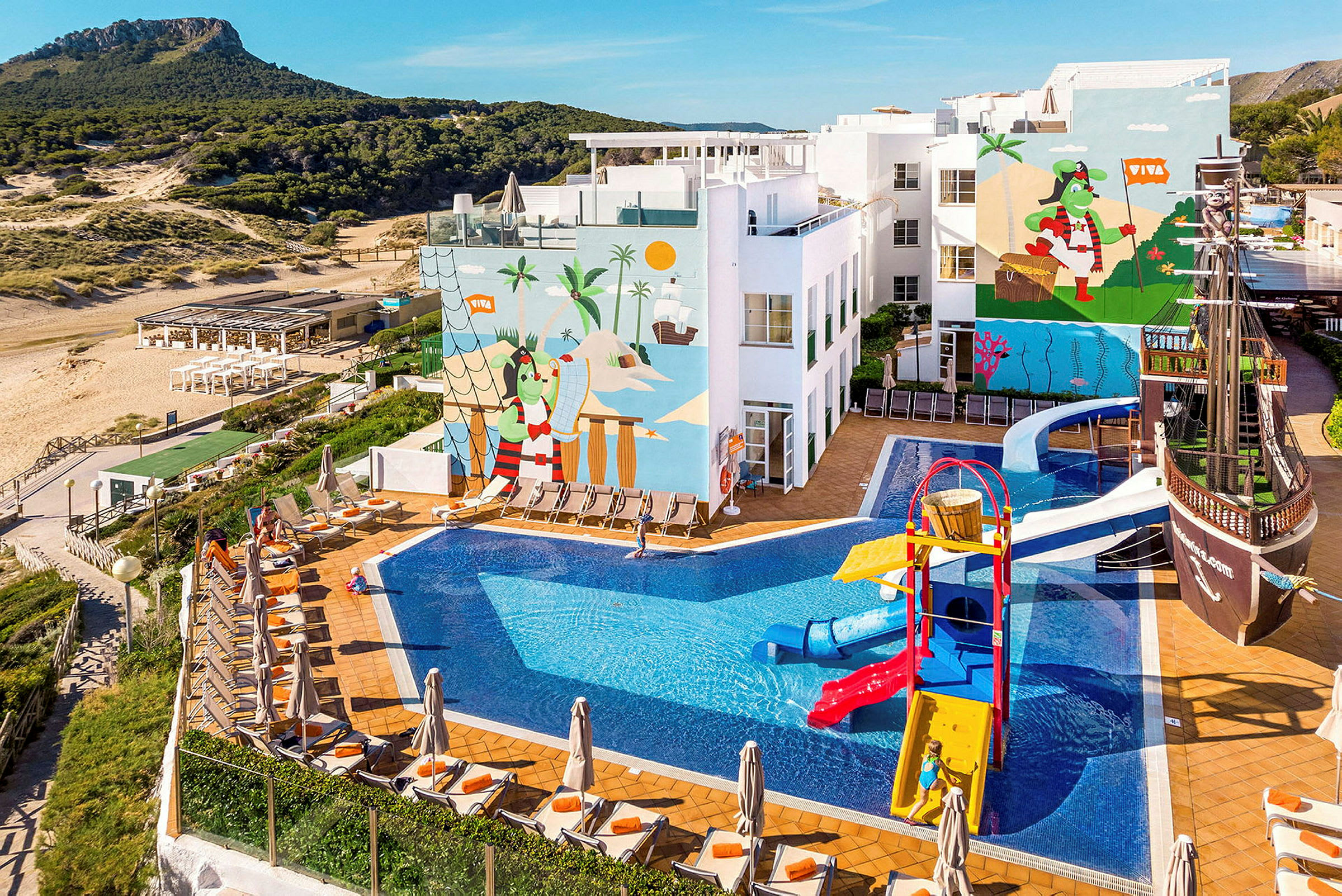 En utomhuspool vid ett hotell med lekplats och närliggande strand. (AI-genererad text)