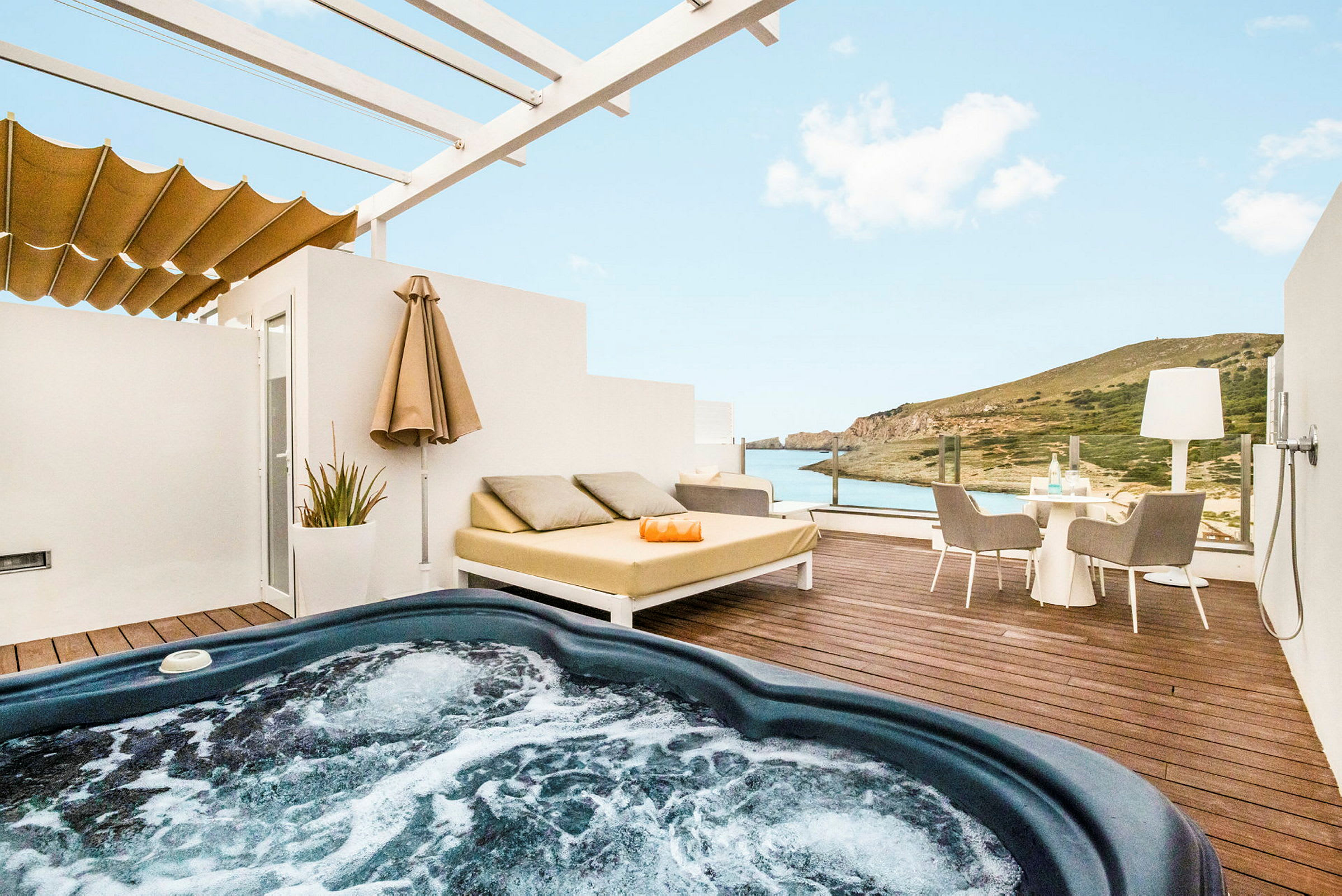 En terrass med bubbelpool, liggande möbler och utsikt över havet och landskapet. (AI-genererad text)