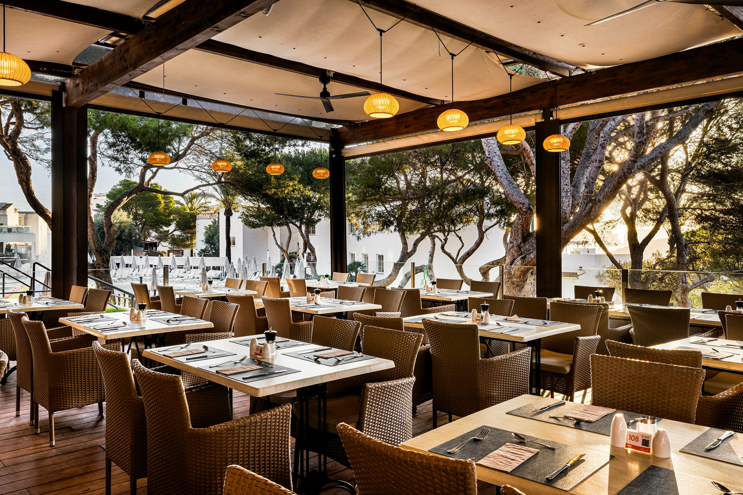 En restaurang med dukade bord och utsikt mot träd utanför. (AI-genererad text)