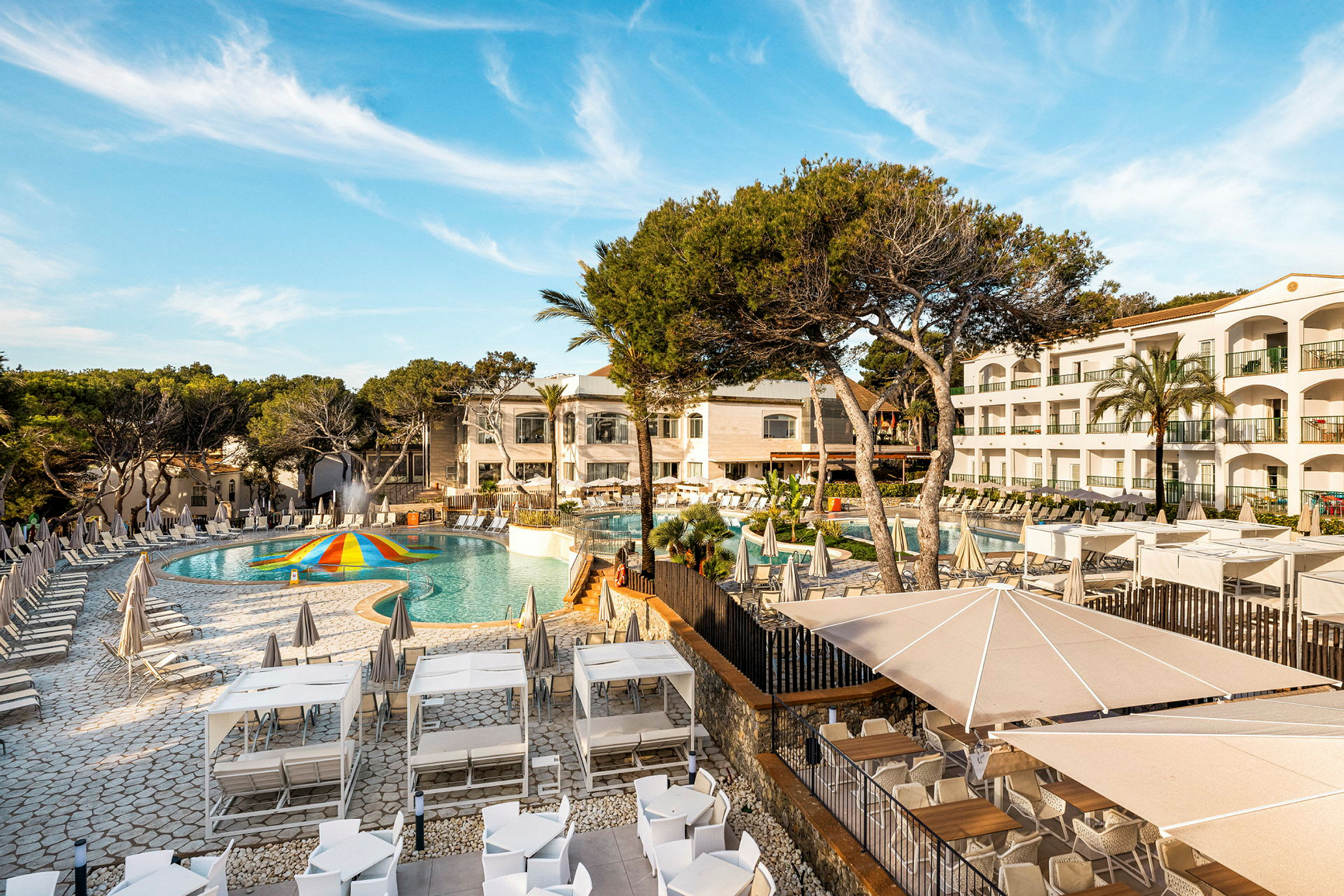 Bild av ett hotellområde med pool, solstolar och grönska. (AI-genererad text)