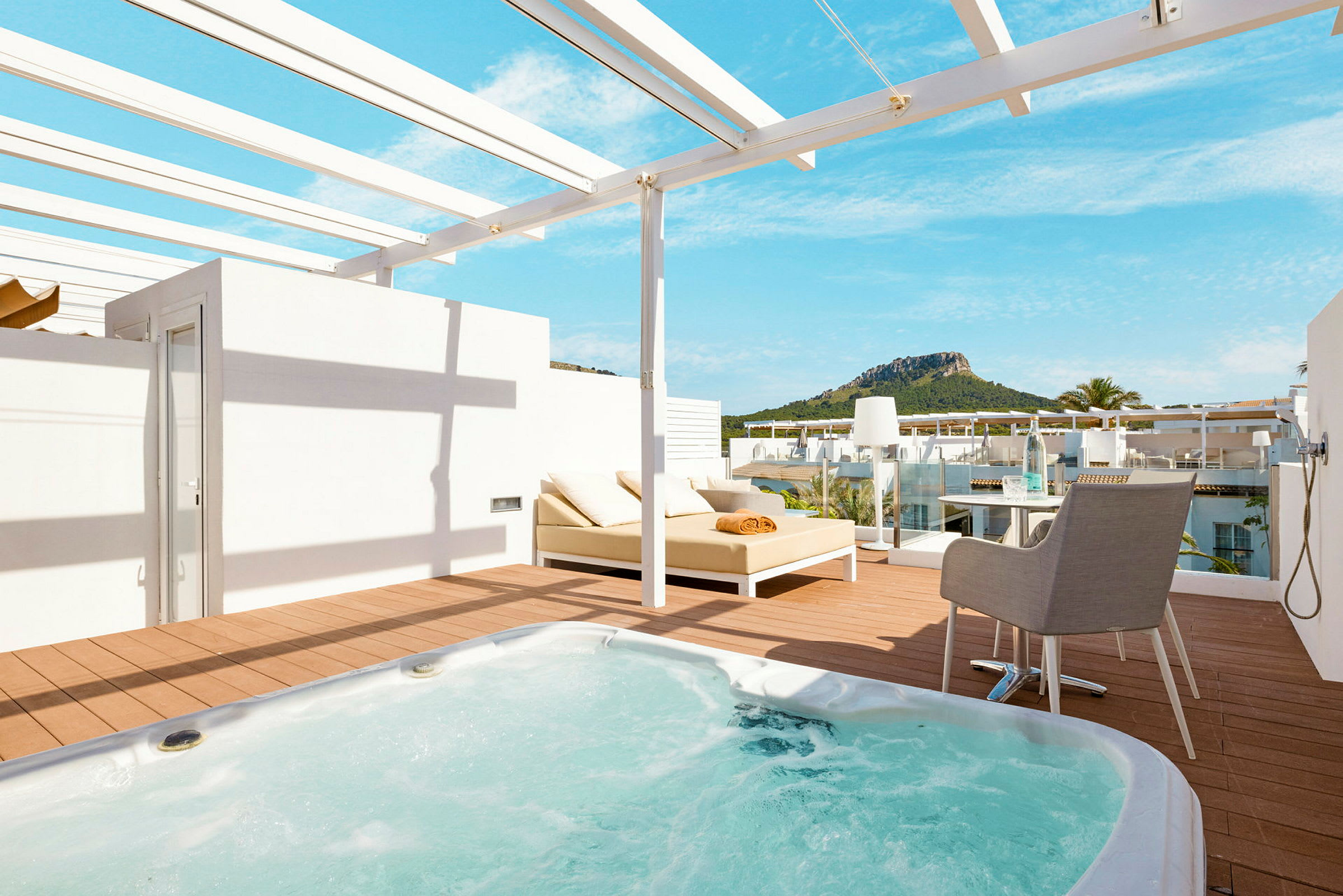 Terrass med jacuzzi, solsäng och utsikt mot grönskande berg. (AI-genererad text)