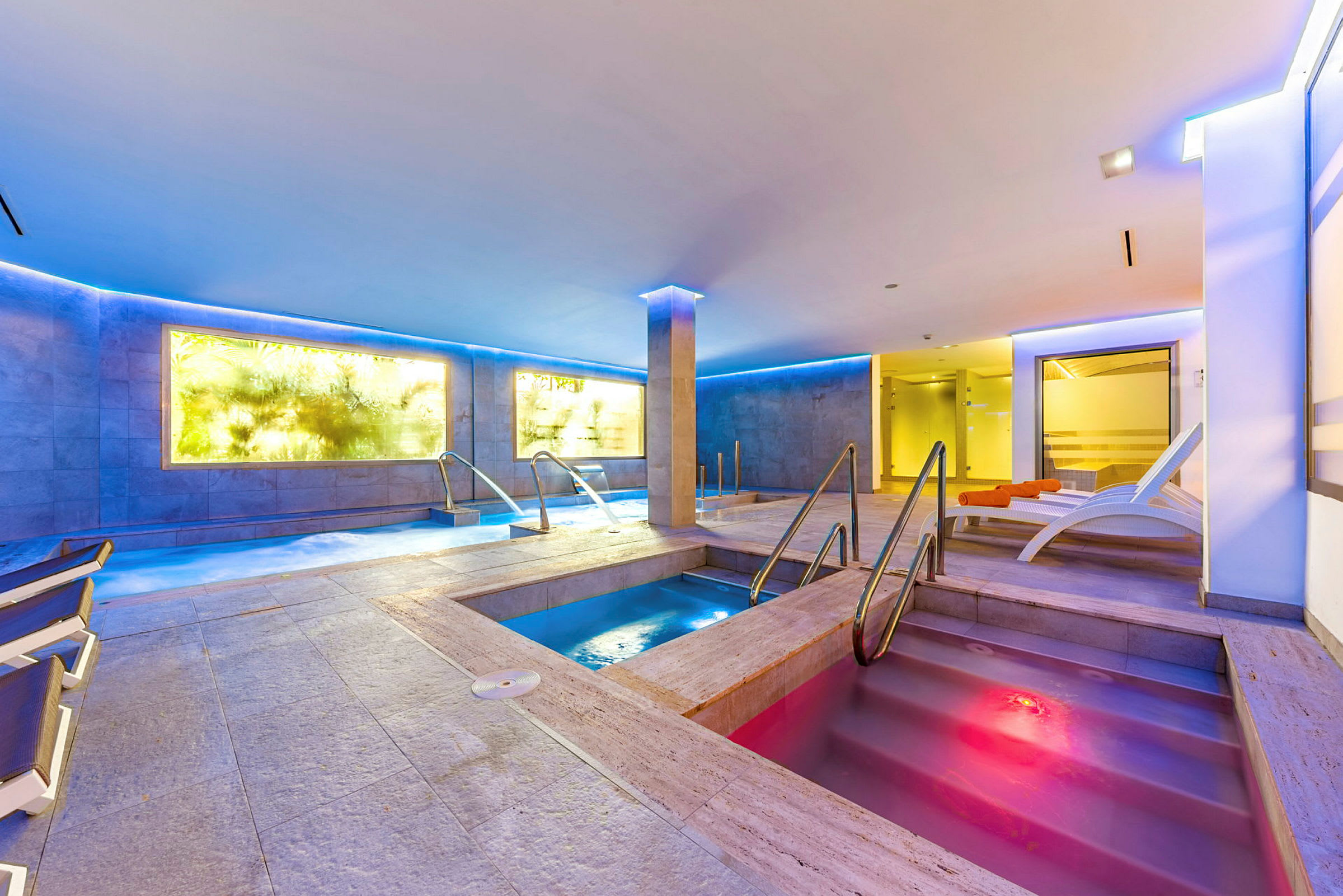 Interiör av ett spa med olika bassänger och stolar. (AI-genererad text)
