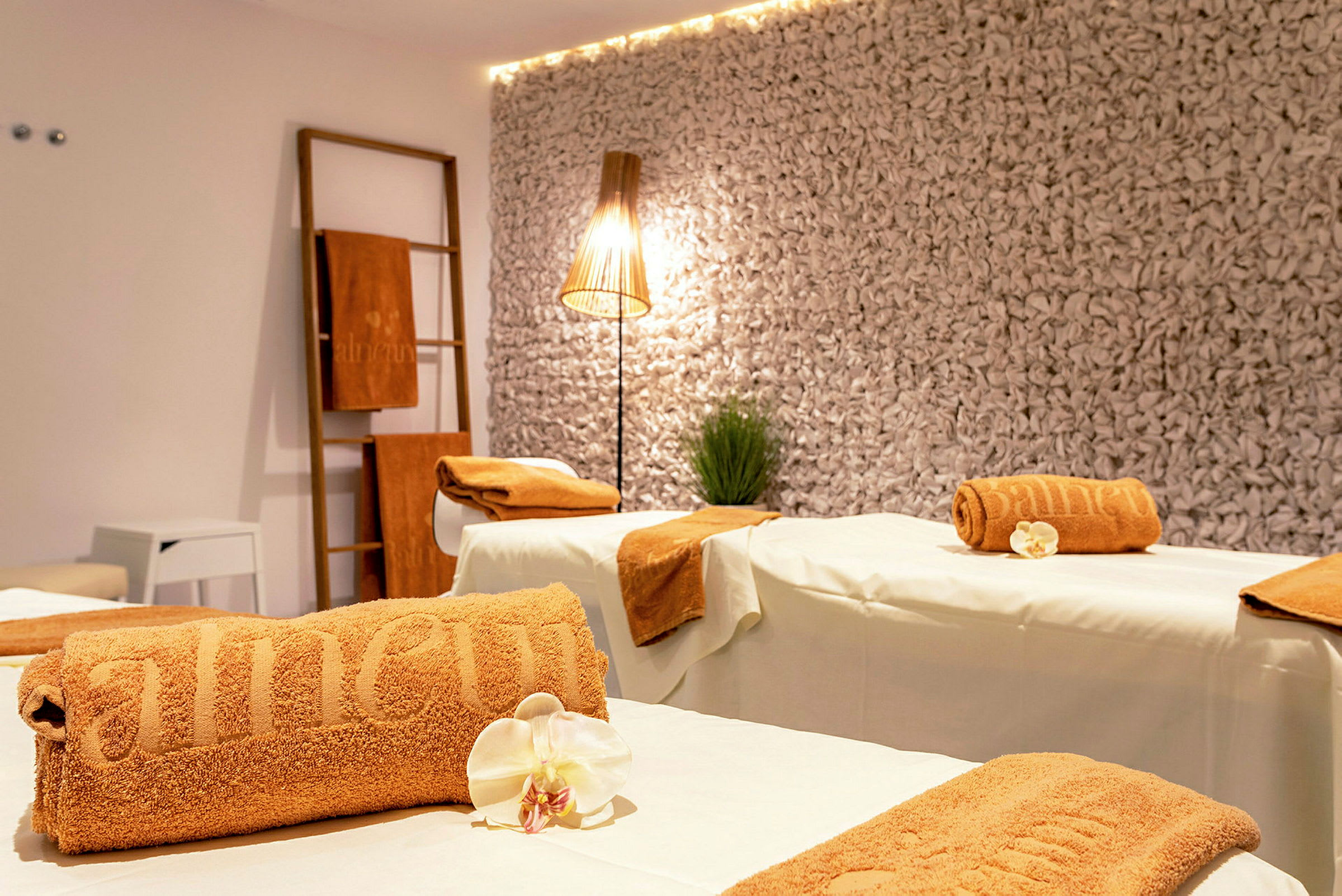 Ett spa-rum med massagebänkar, bruna handdukar och dekorativ belysning. (AI-genererad text)