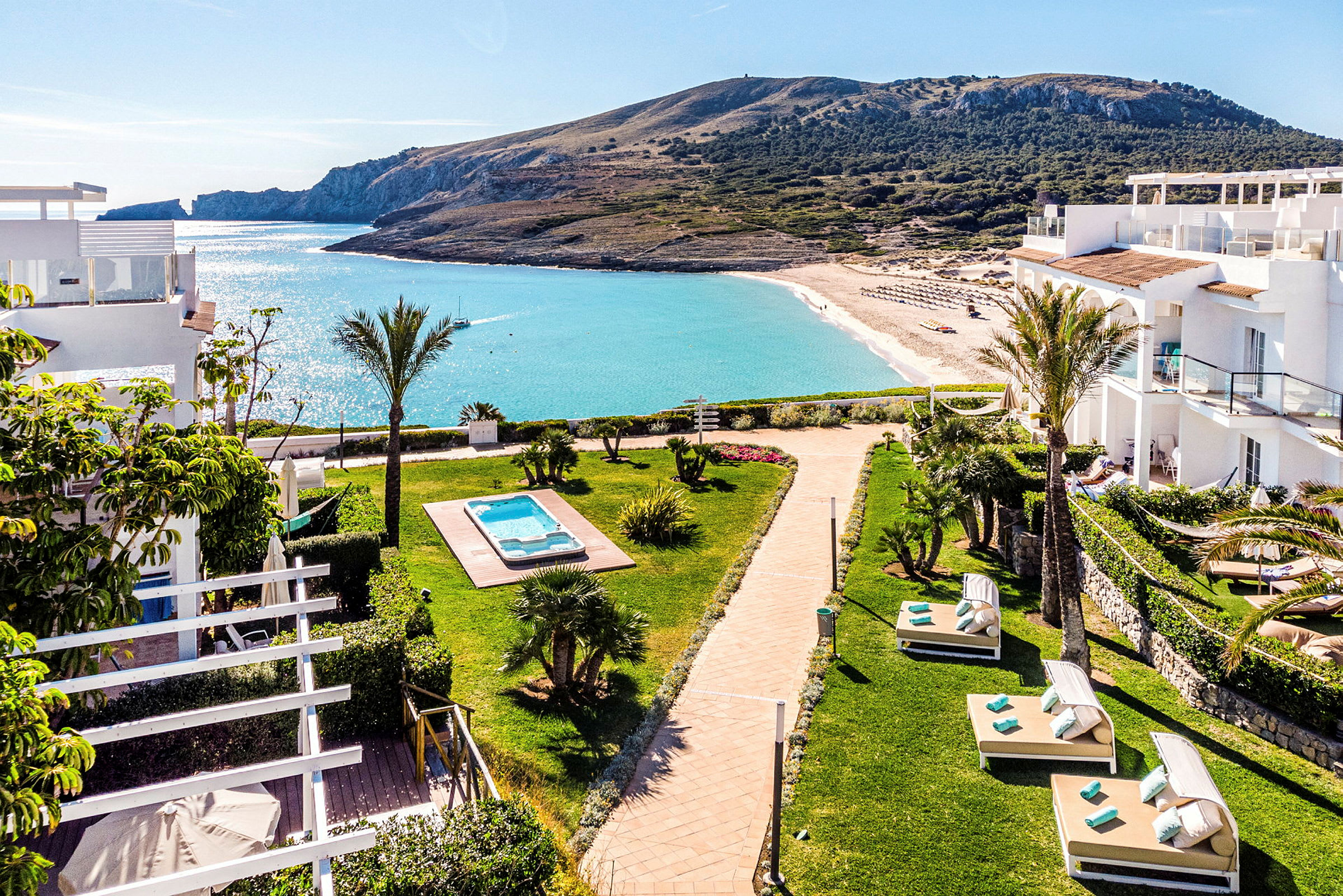 Vy över hotellområde med solsängar, pool och strand i bakgrunden. (AI-genererad text)