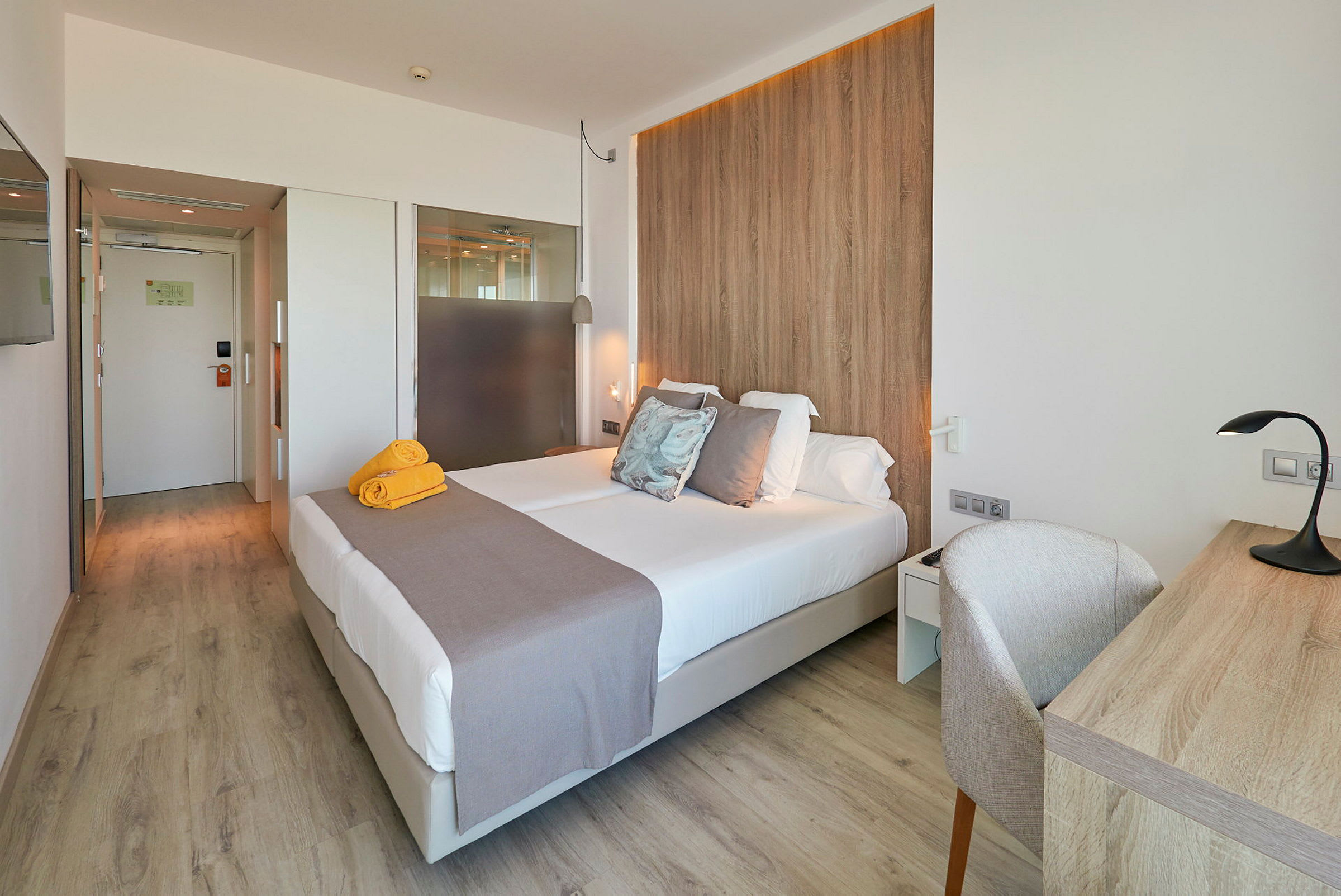 Ett hotellrum med en dubbelsäng, skrivbord och trädetaljer. (AI-genererad text)