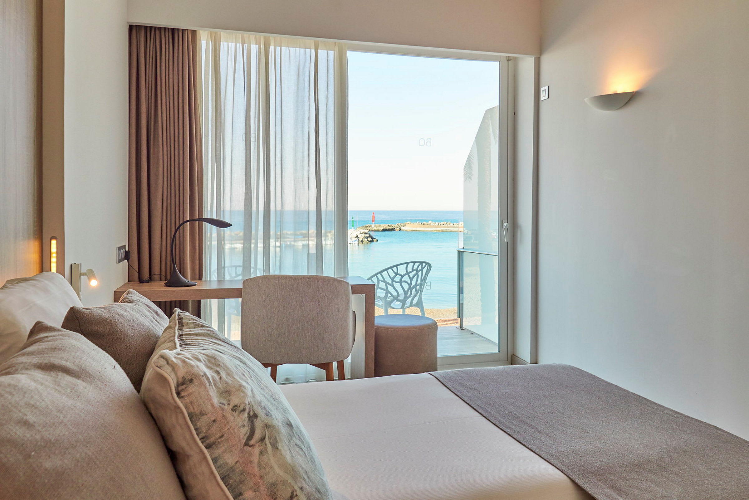 Ett hotellrum med utsikt över havet genom fönstret. (AI-genererad text)