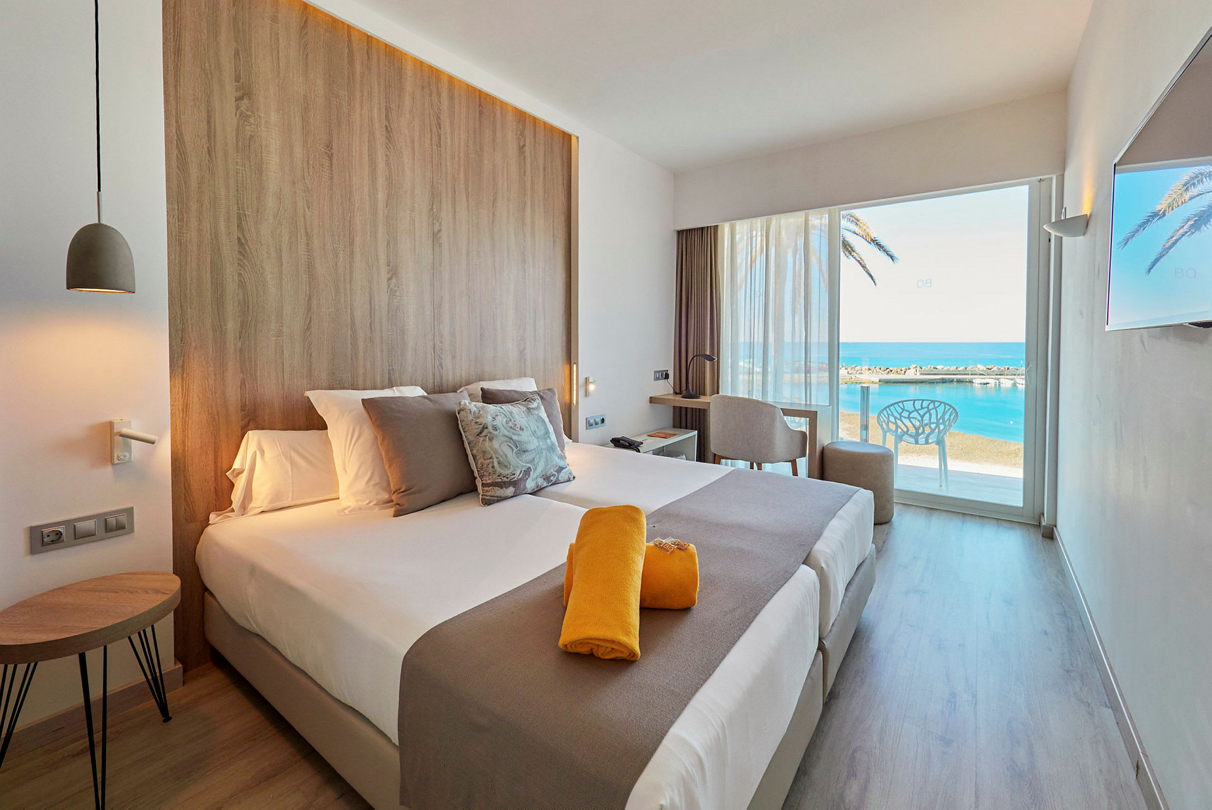 Modernt hotellrum med utsikt över havet genom en stor glasdörr. (AI-genererad text)