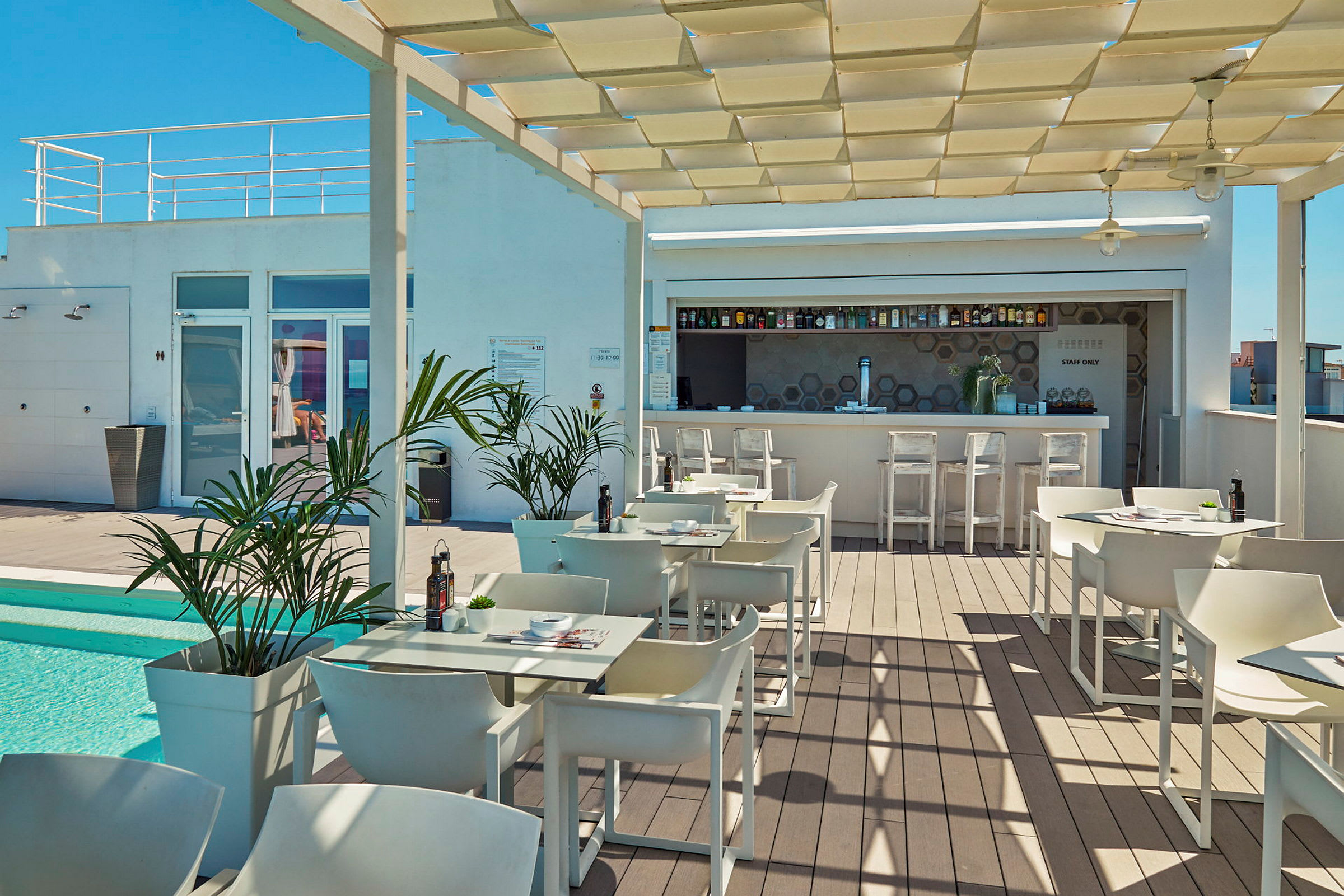 Utomhusservering med bord, stolar och en bar vid en liten pool. (AI-genererad text)