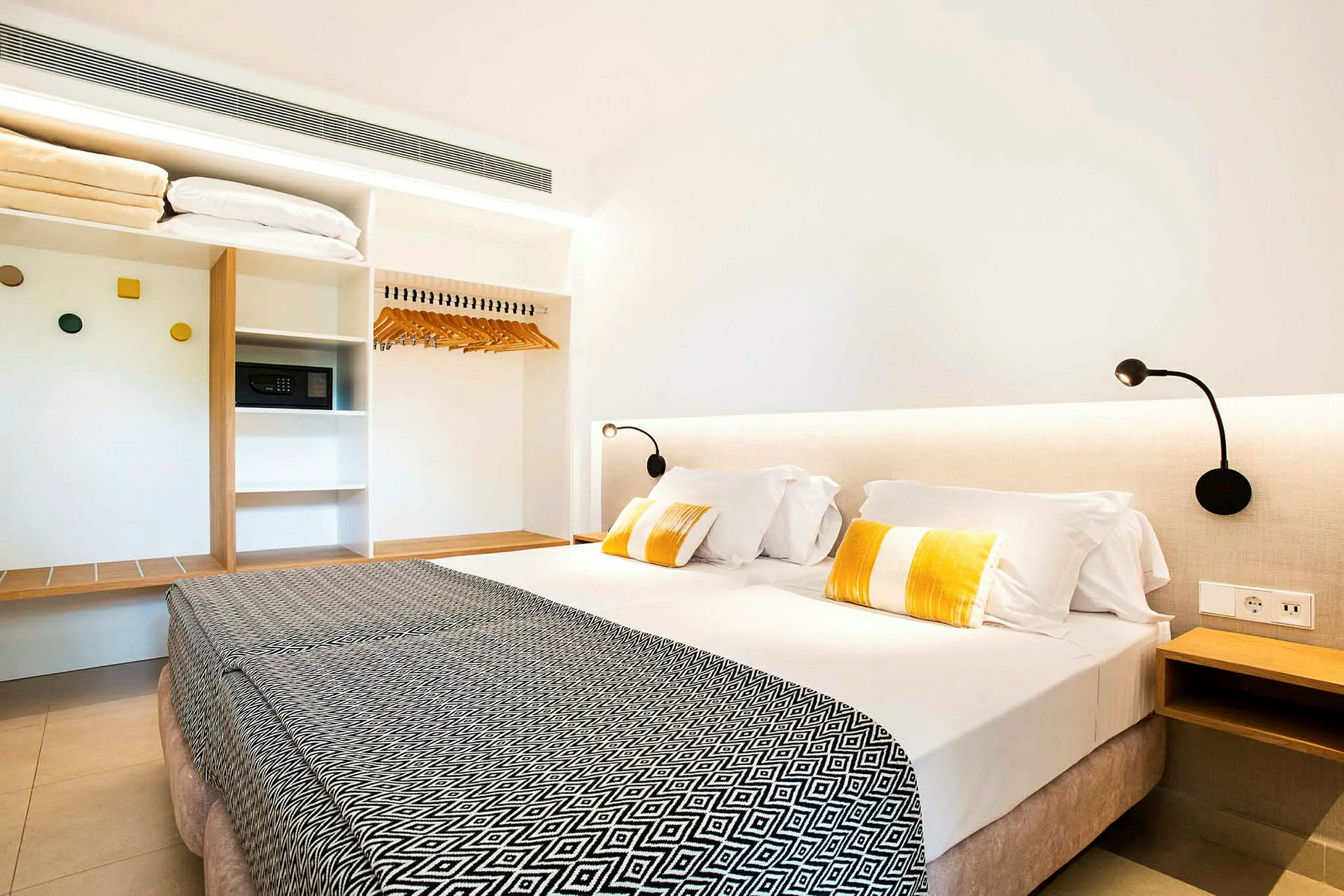 Hotellrum med en dubbelsäng, sänglampor, och en garderob. (AI-genererad text)