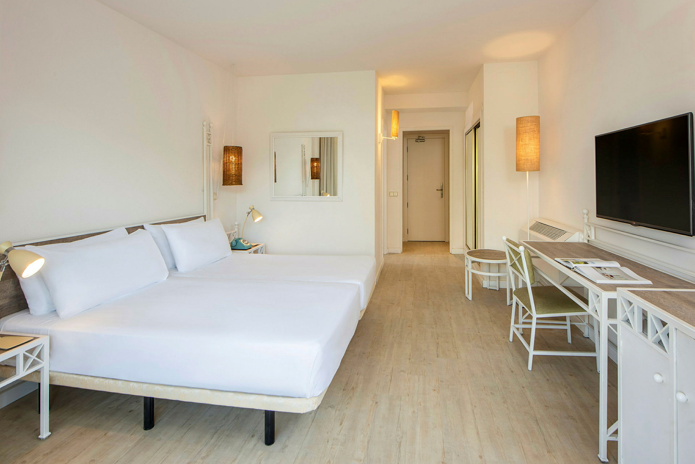 Ett hotellrum med två sängar på vänster sida, en skrivbord med stol till höger och en TV på väggen. (AI-genererad text)