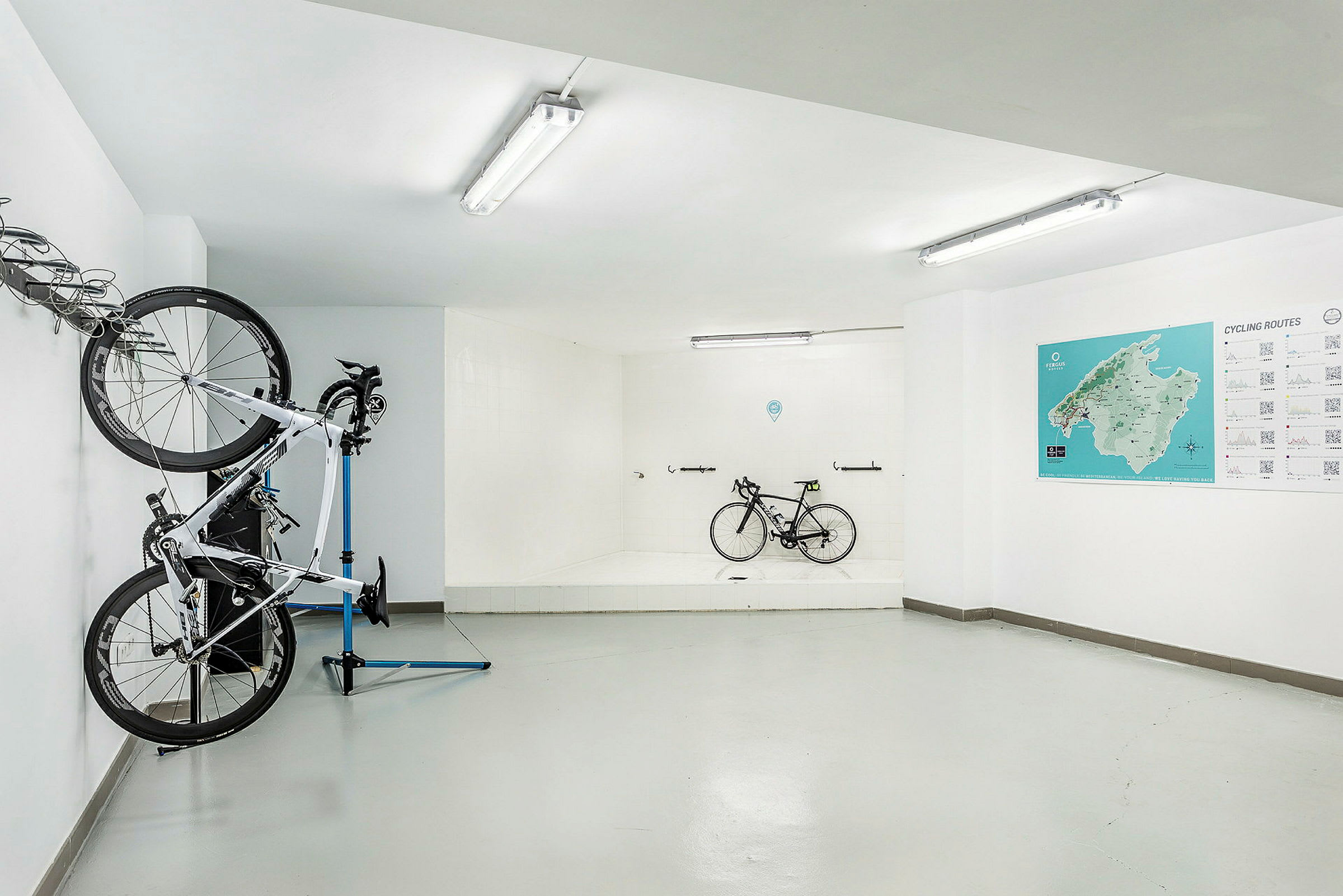 Cykelrum med hängande och stående cyklar samt karta och information på väggen. (AI-genererad text)