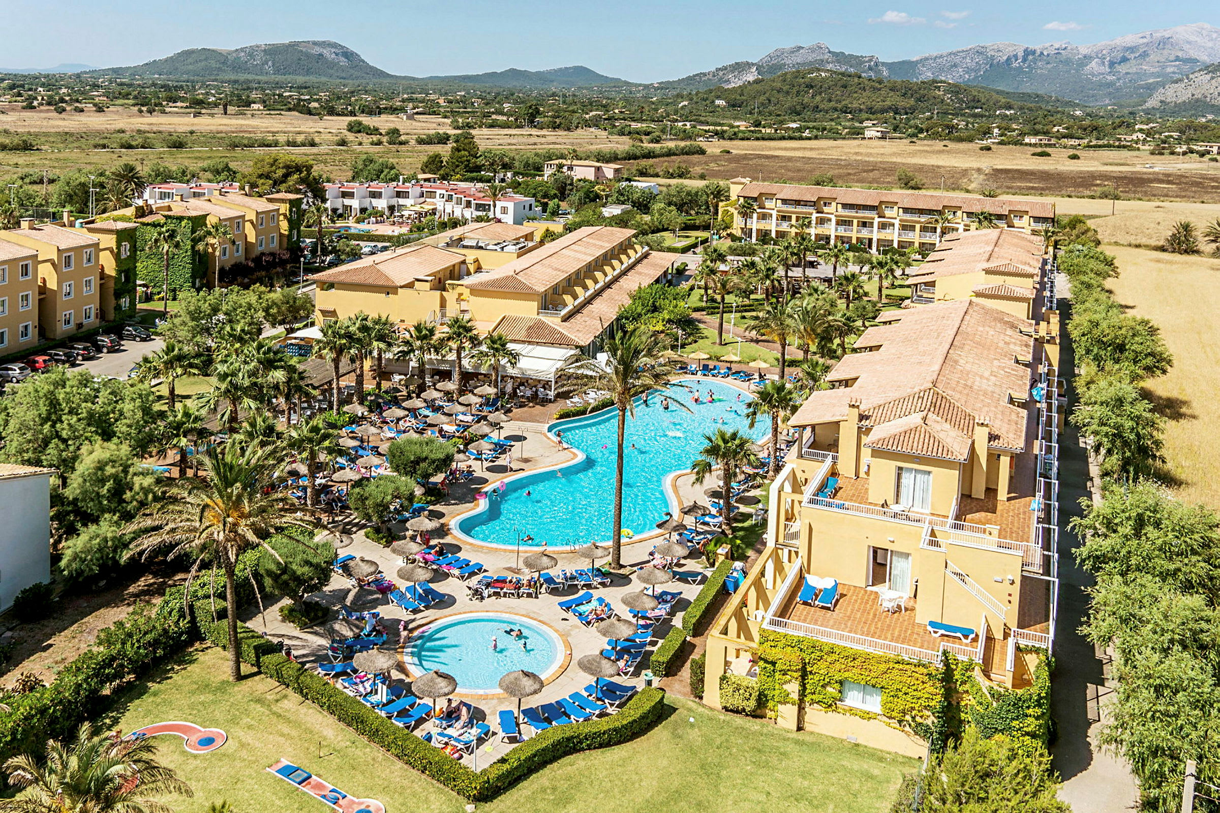 Hotellområde med flera byggnader och två pooler. (AI-genererad text)