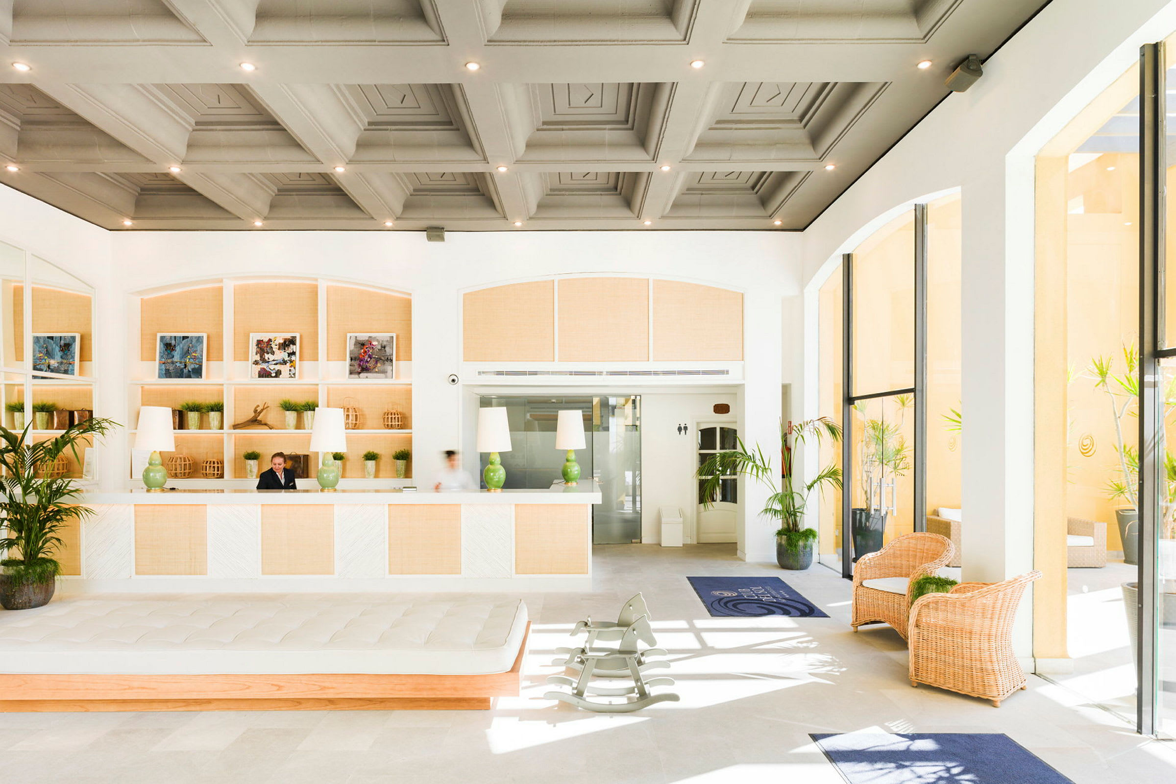 Ljus och rymlig hotellobby med reception, växter och sittplatser. (AI-genererad text)