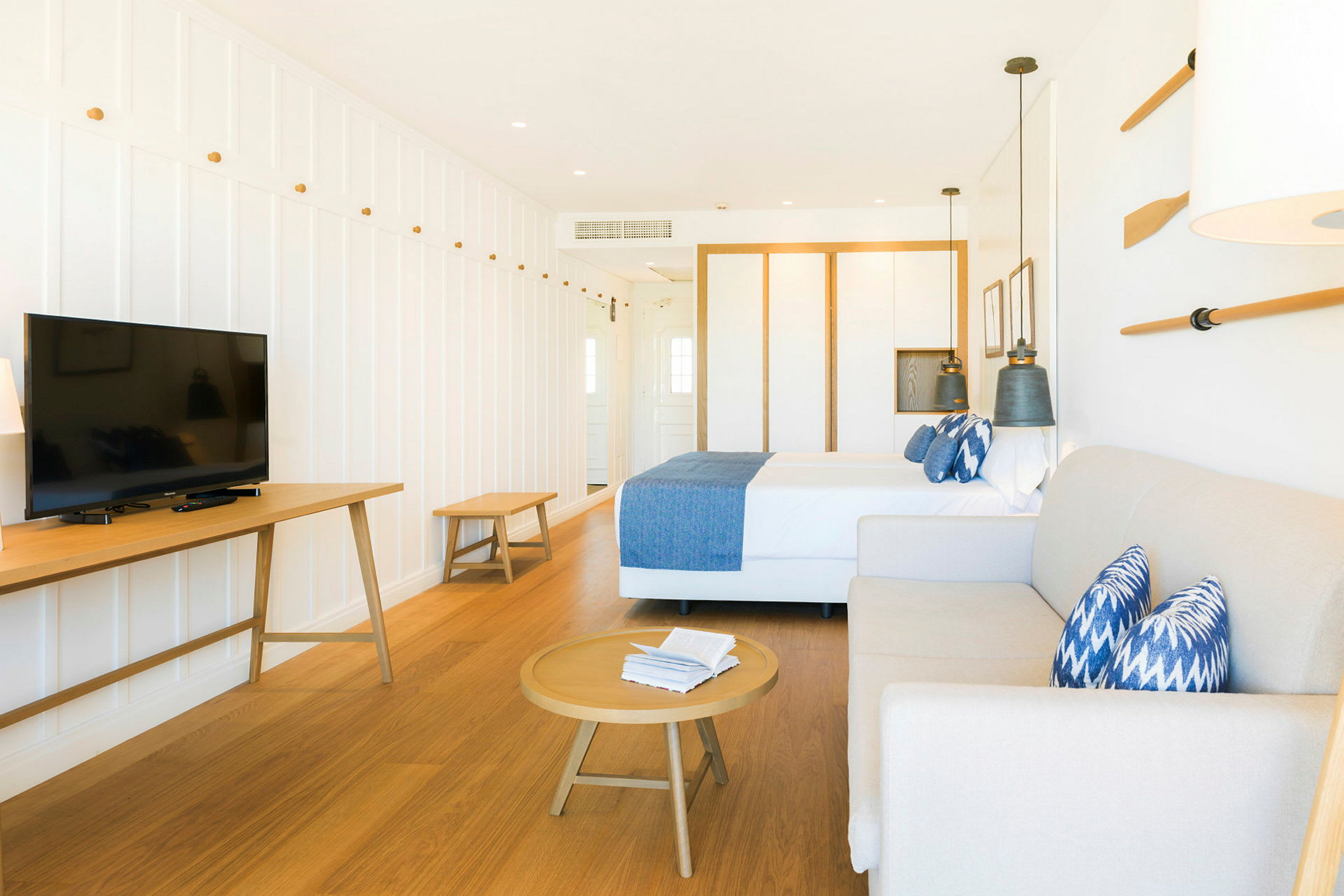 Ett ljust inrett hotellrum med säng, soffa, soffbord och TV. (AI-genererad text)
