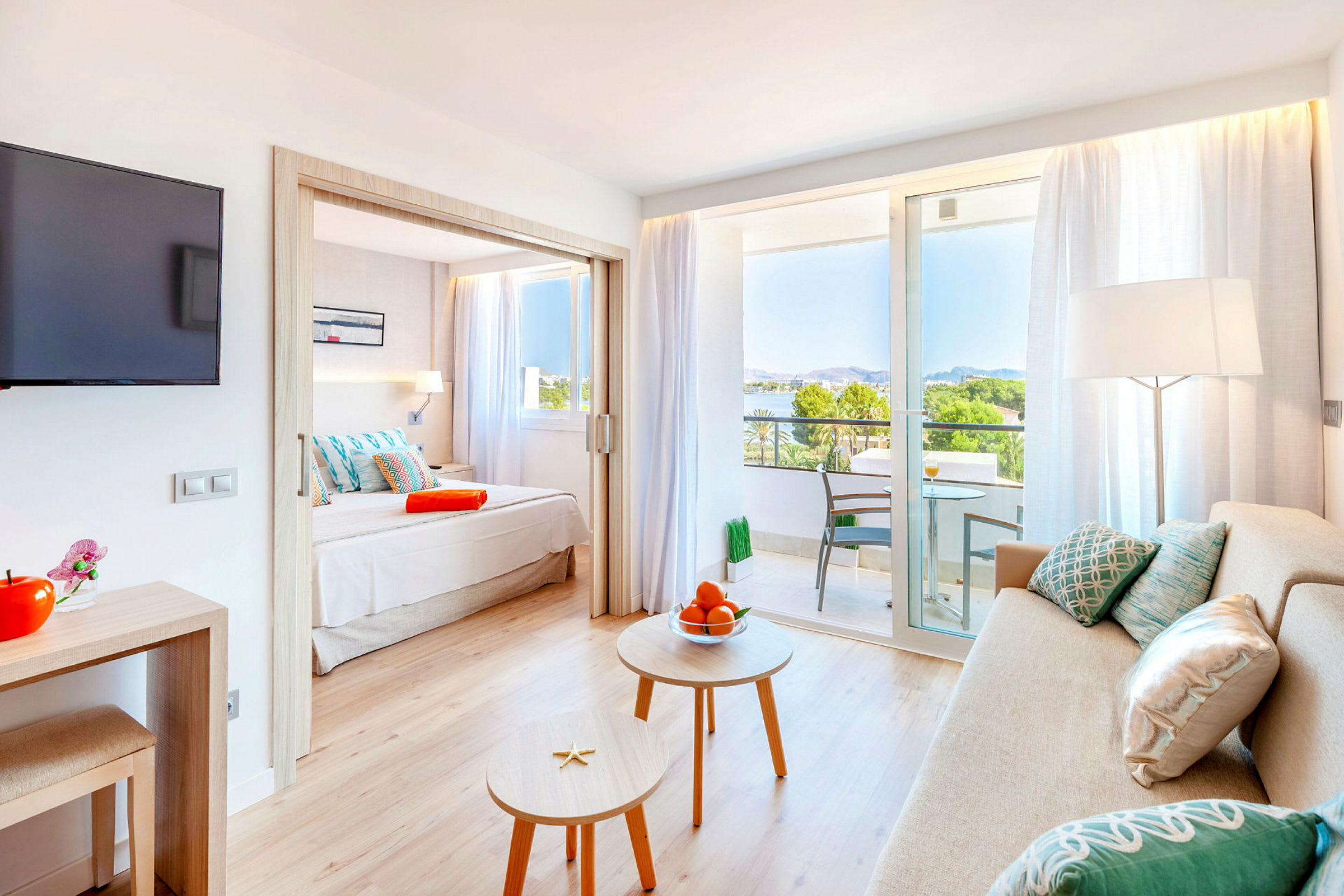 Inredning av ett hotellrum med soffa, bord, en säng och en balkong med utsikt. (AI-genererad text)