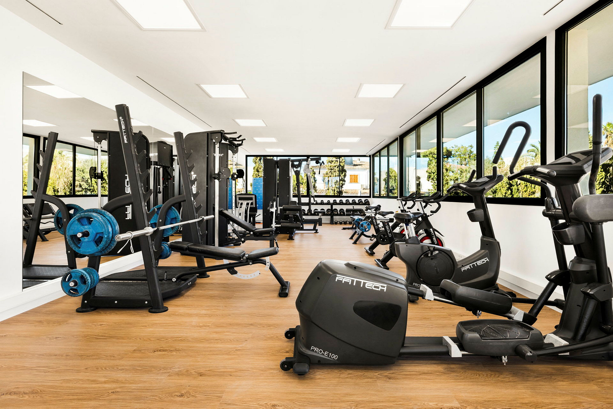 Ett modernt gym med träningsmaskiner, cyklar och vikter, samt stora fönster som släpper in naturligt ljus. (AI-genererad text)