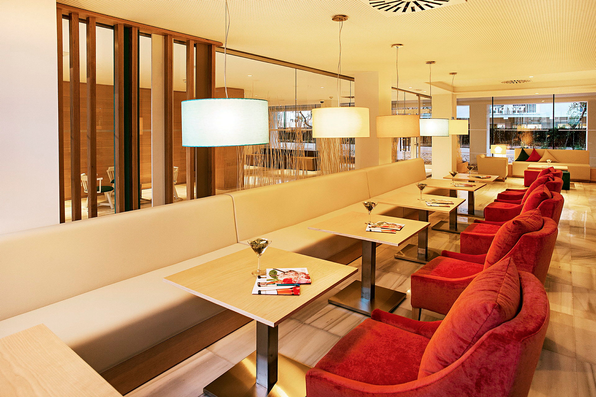 Moderna sittplatser med bord, soffor och röda fåtöljer i ett belyst rum. (AI-genererad text)