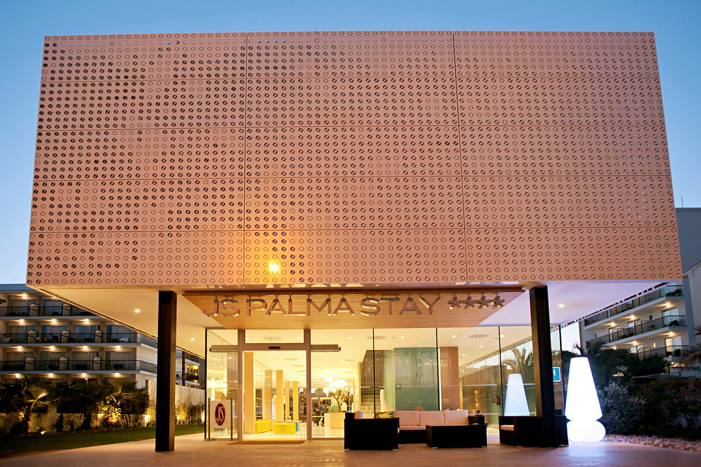 Hotellfasad med modern design, synliga fönster och entréområde med belysning. (AI-genererad text)