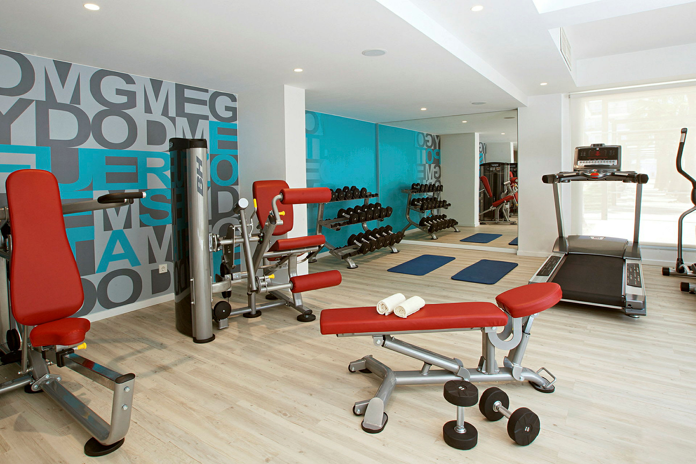 Ett gym med träningsmaskiner, hantlar och yogamattor. (AI-genererad text)
