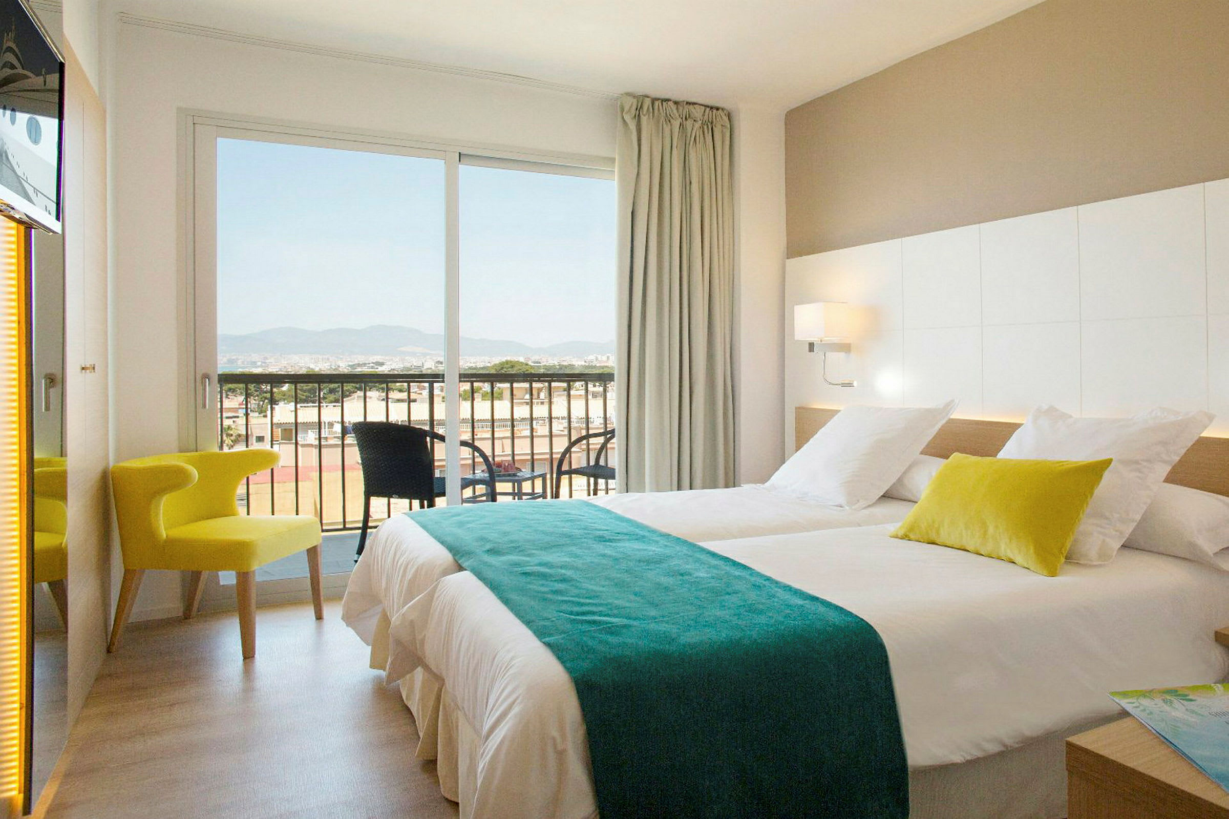 Ett hotellrum med två sängar, en stol och en balkong med utsikt. (AI-genererad text)