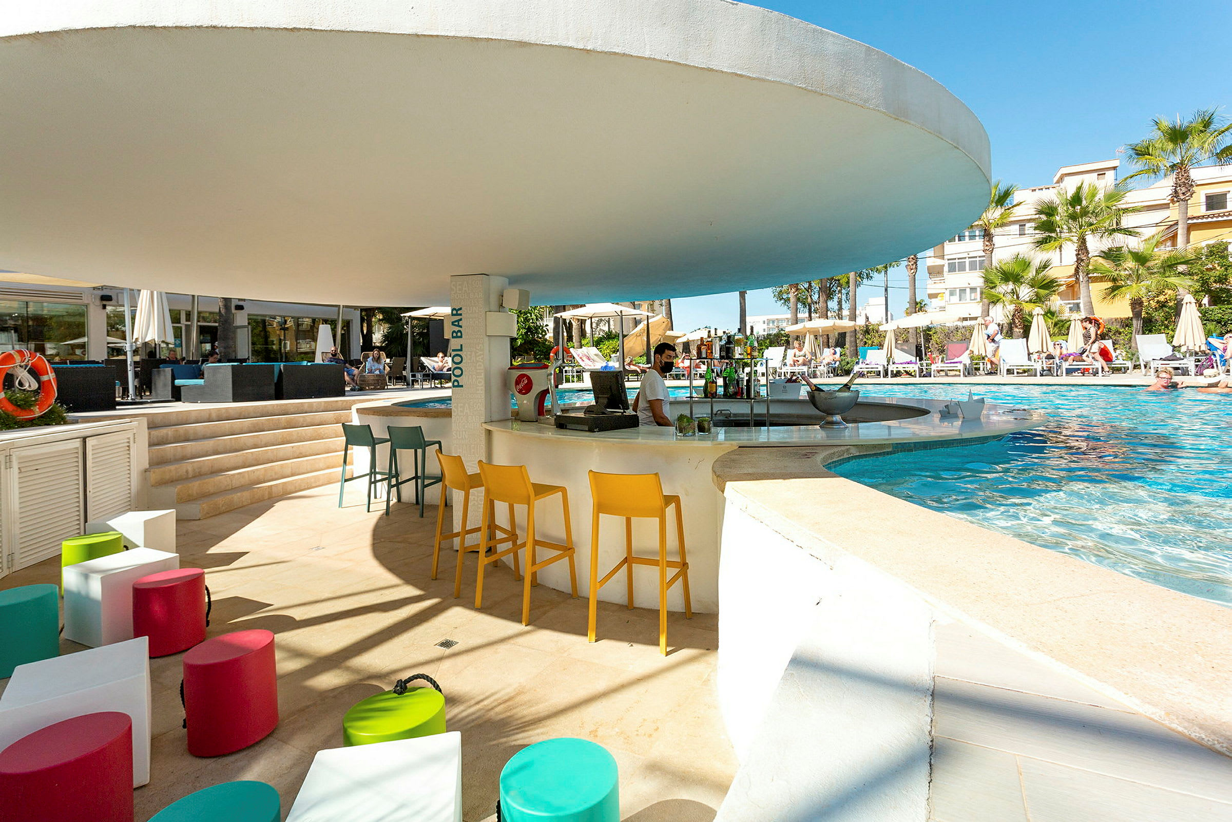 Utomhuspoolområde med poolbar och färgglada sittplatser. (AI-genererad text)