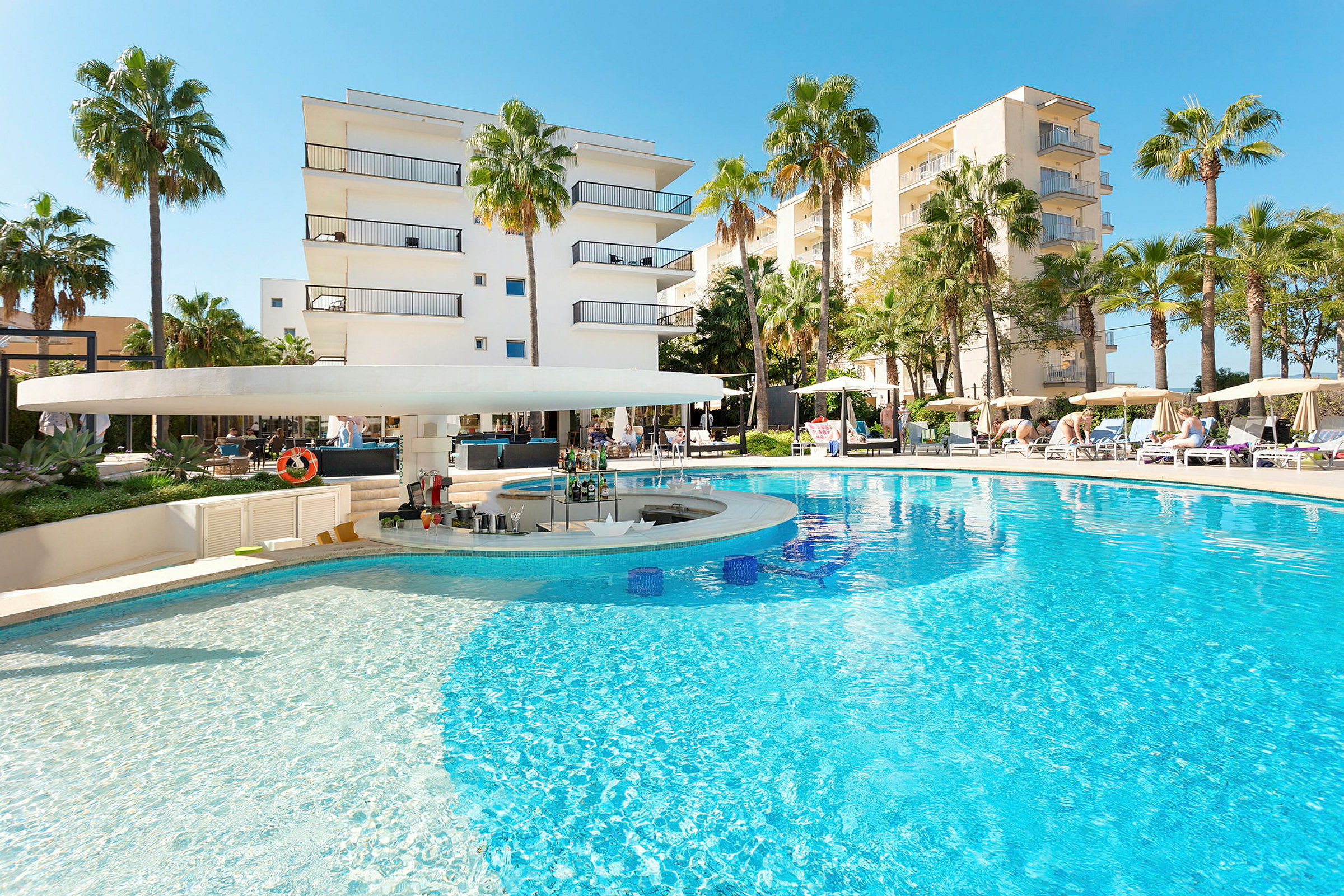 Bild av en pool med bar och omgivande solstolar samt byggnader i bakgrunden. (AI-genererad text)