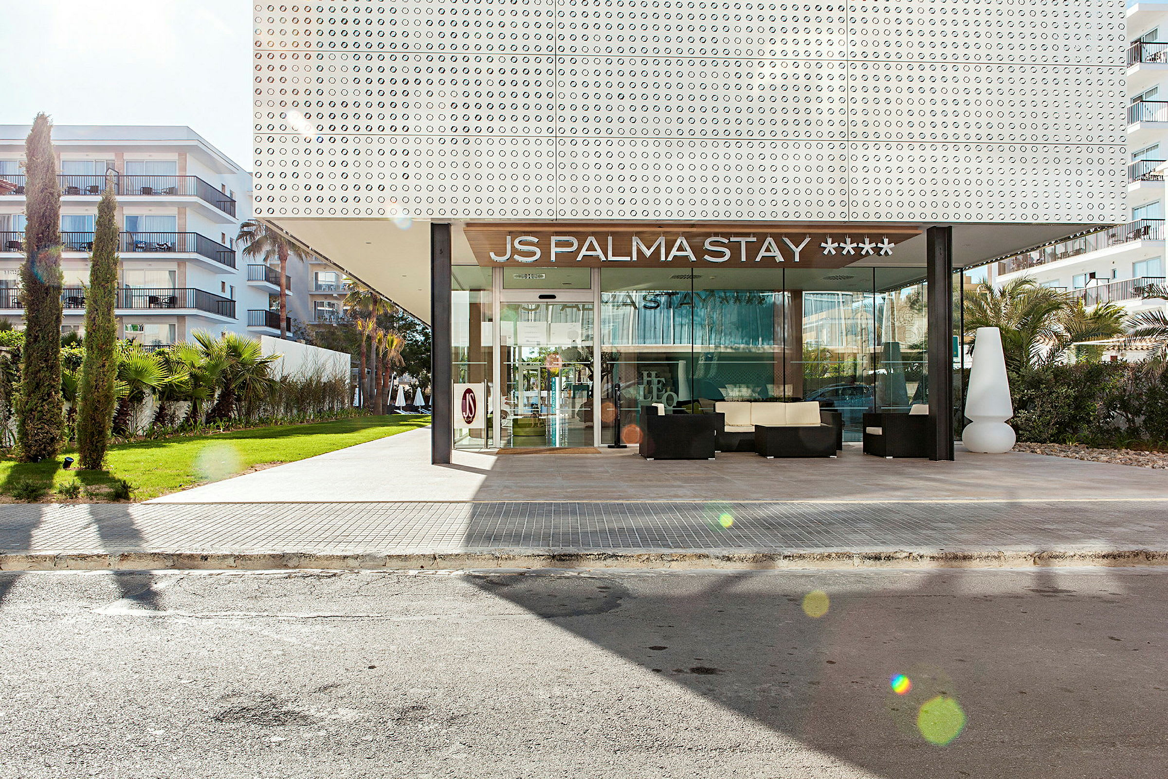 Exteriör av JS Palma Stay hotell med ingång och omgivande grönska. (AI-genererad text)