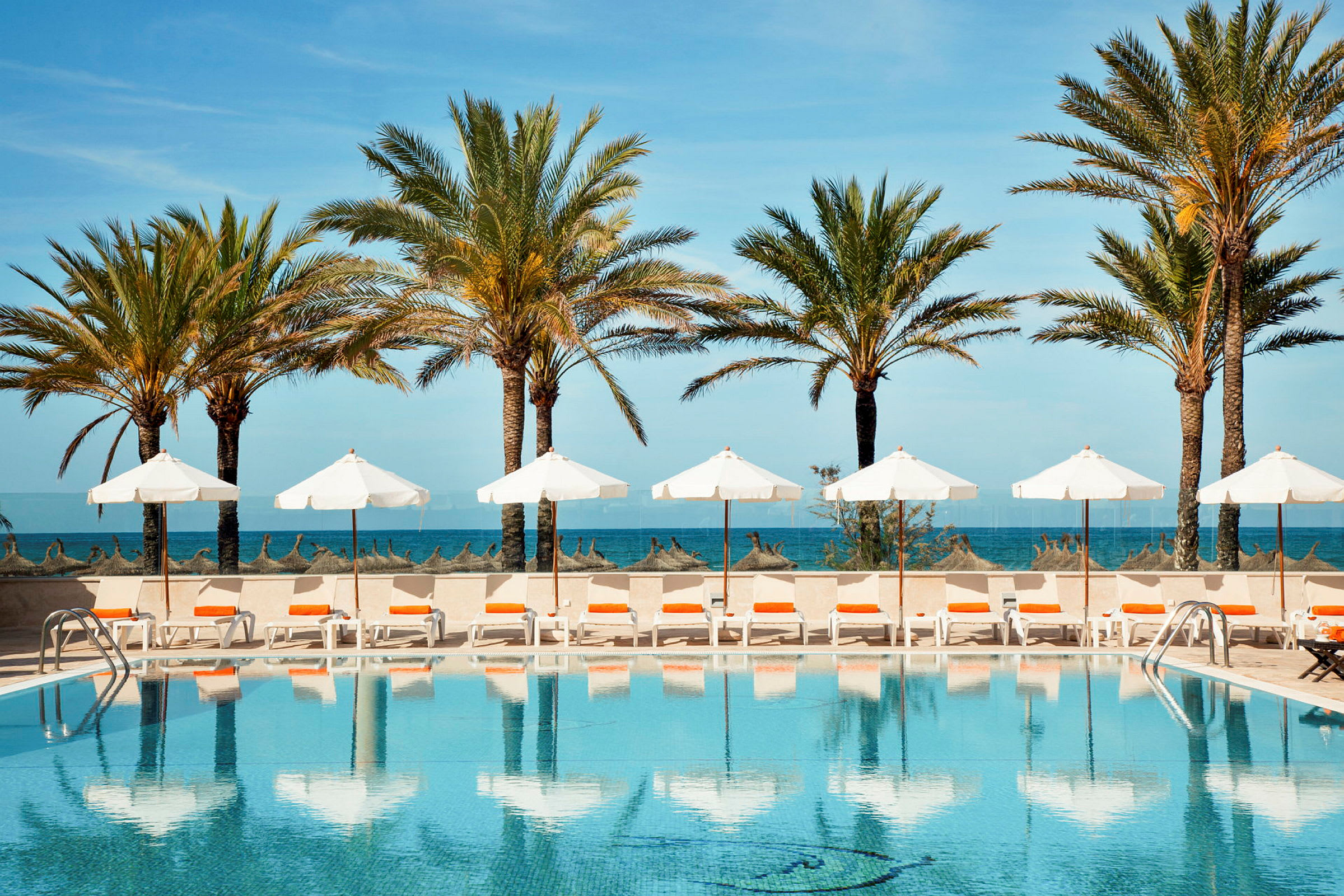 En pool med parasoller och solstolar vid havet. (AI-genererad text)