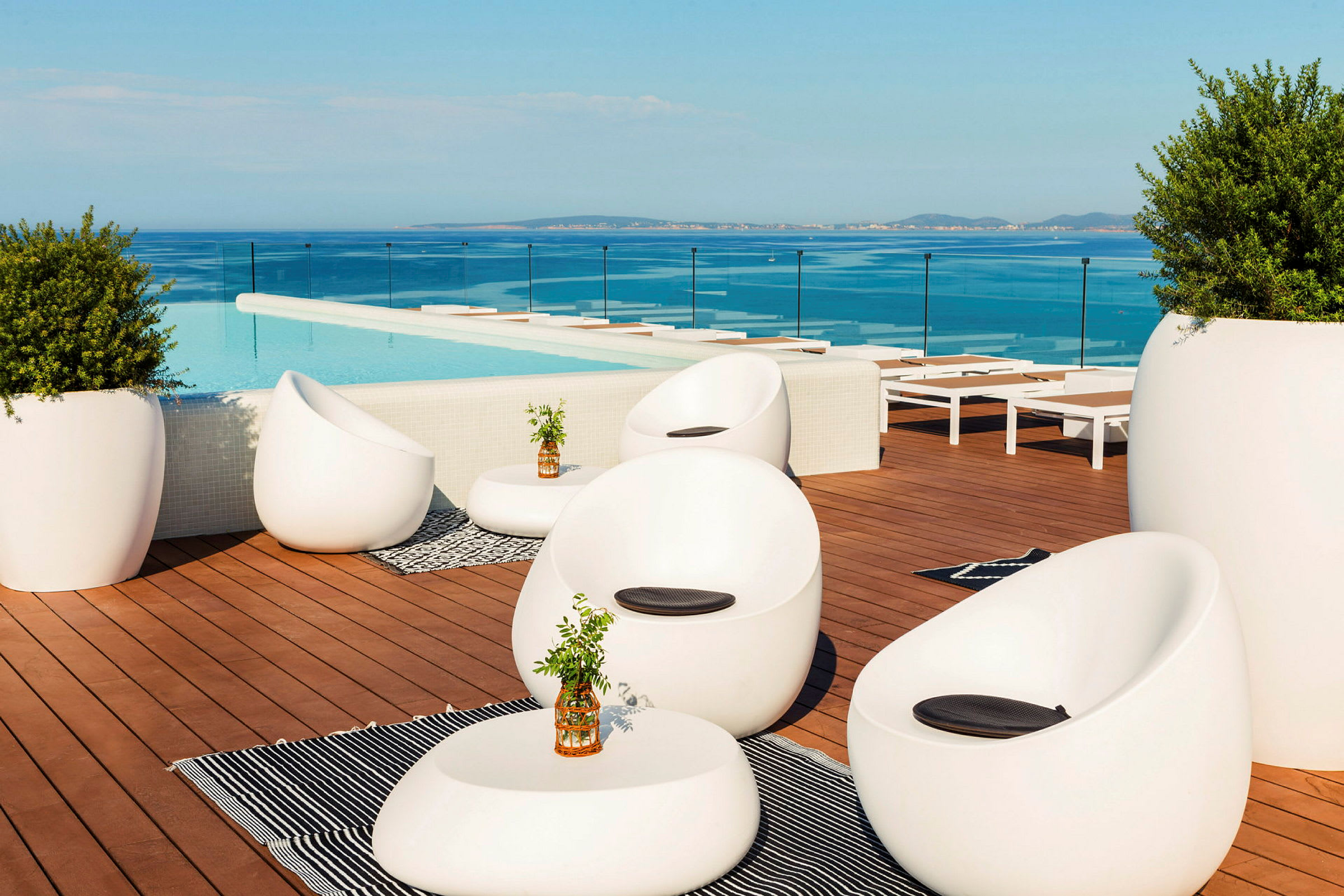 Loungeområde vid en pool med moderna möbler och utsikt över havet. (AI-genererad text)