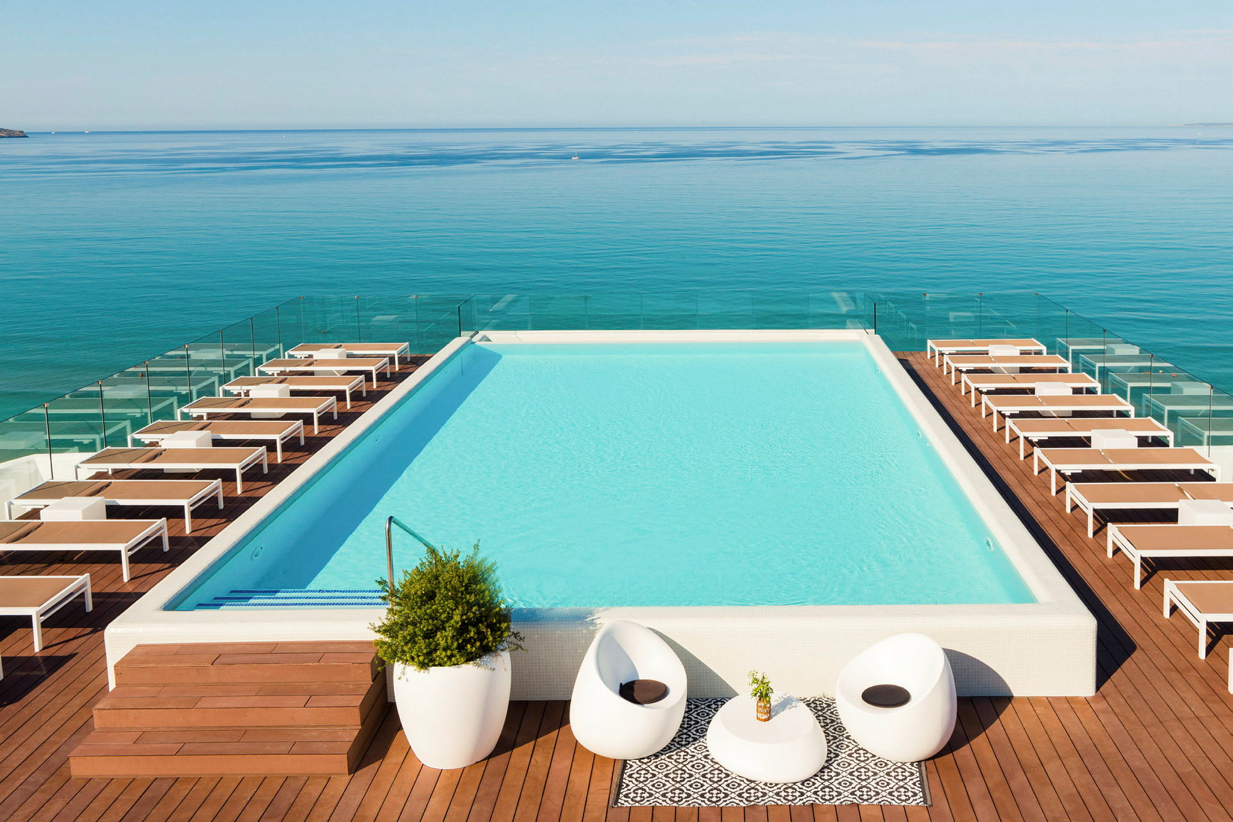 Upphöjd pool med solstolar runtom och utsikt över havet. (AI-genererad text)